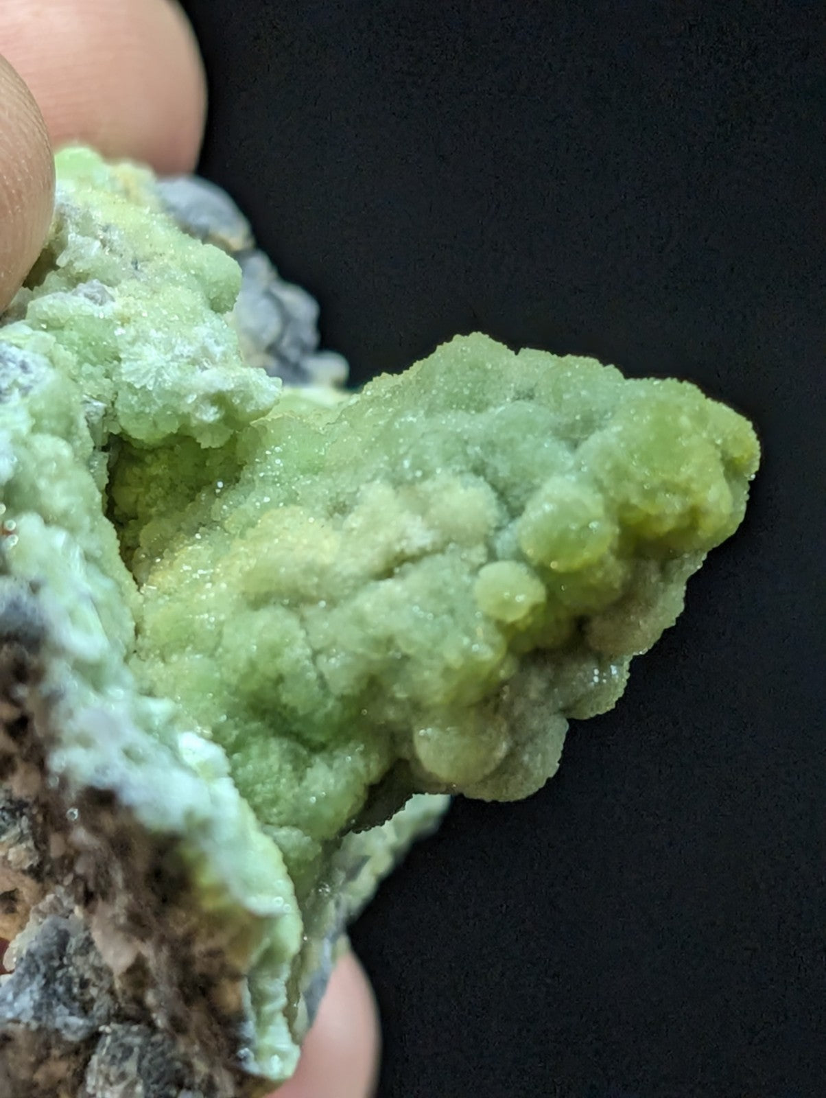 A vibrant green, crystalline mineral specimen with a textured, bumpy surface and translucent quality.