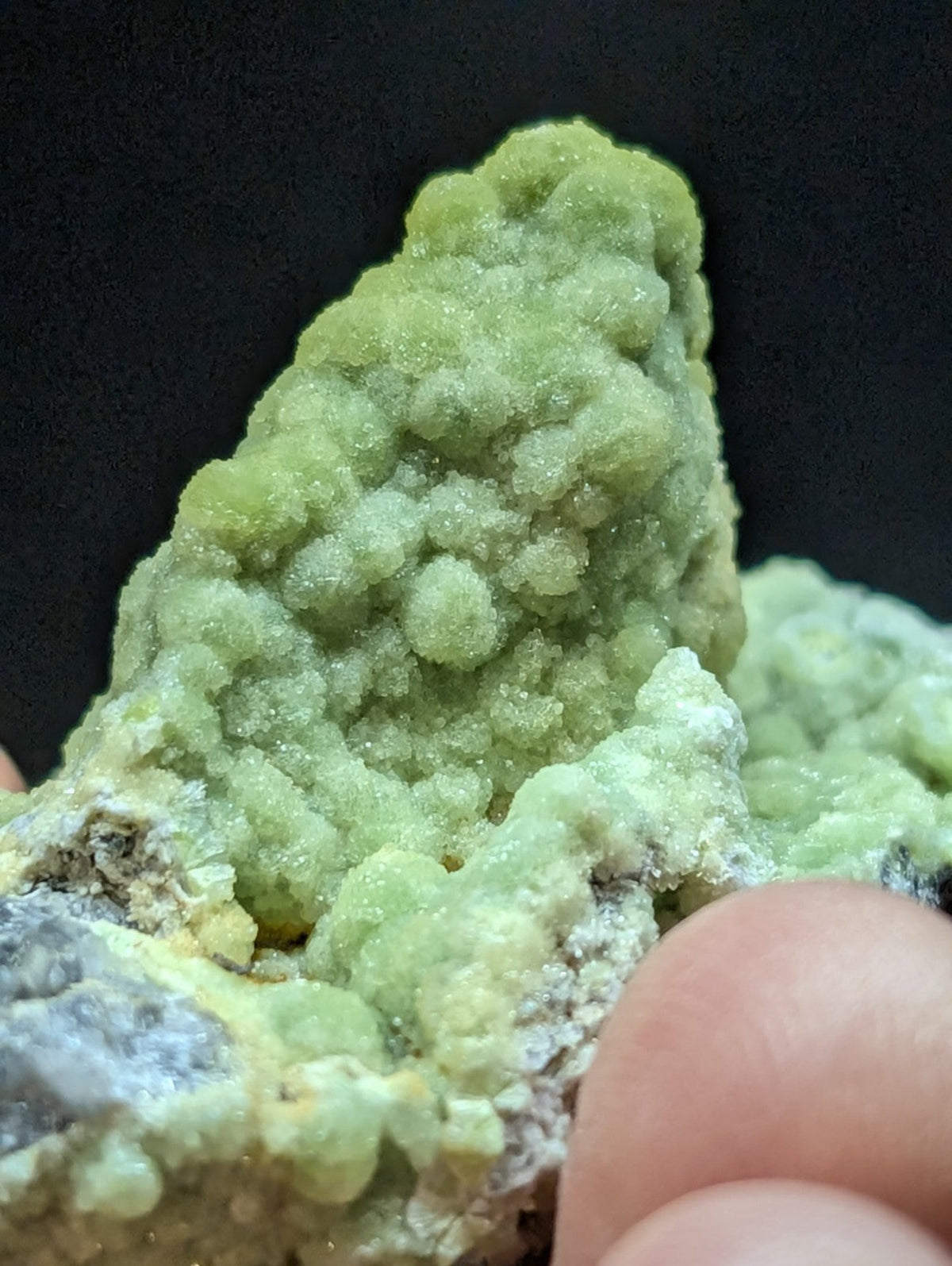 A vibrant green, bumpy mineral specimen with a textured surface and crystalline formations.
