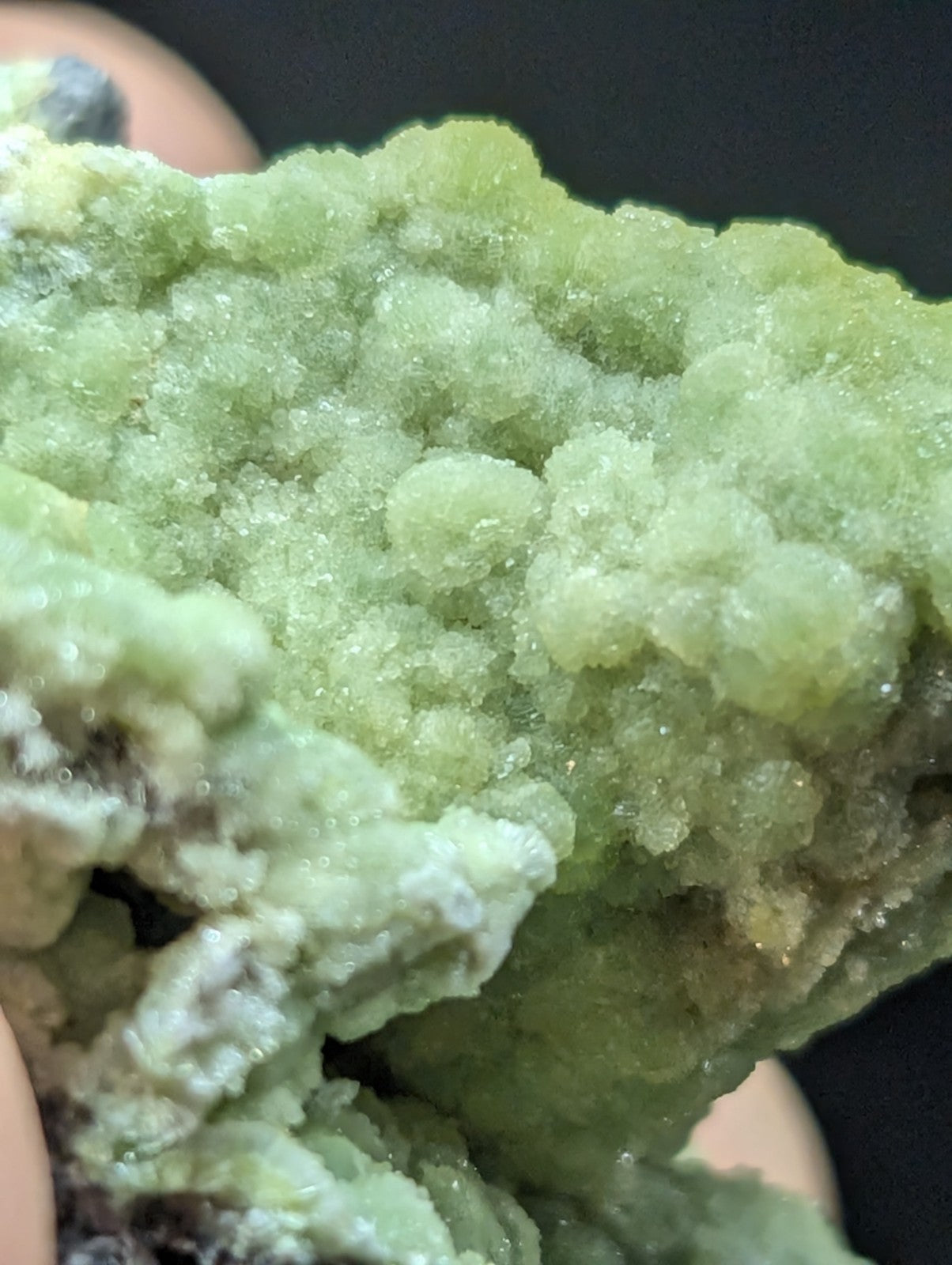 A vibrant green, crystalline mineral specimen with a textured, bumpy surface and translucent facets.