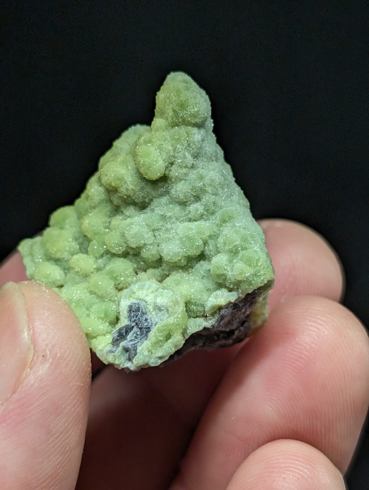 A textured, light green mineral specimen with a rough, bumpy surface and subtle crystalline formations.