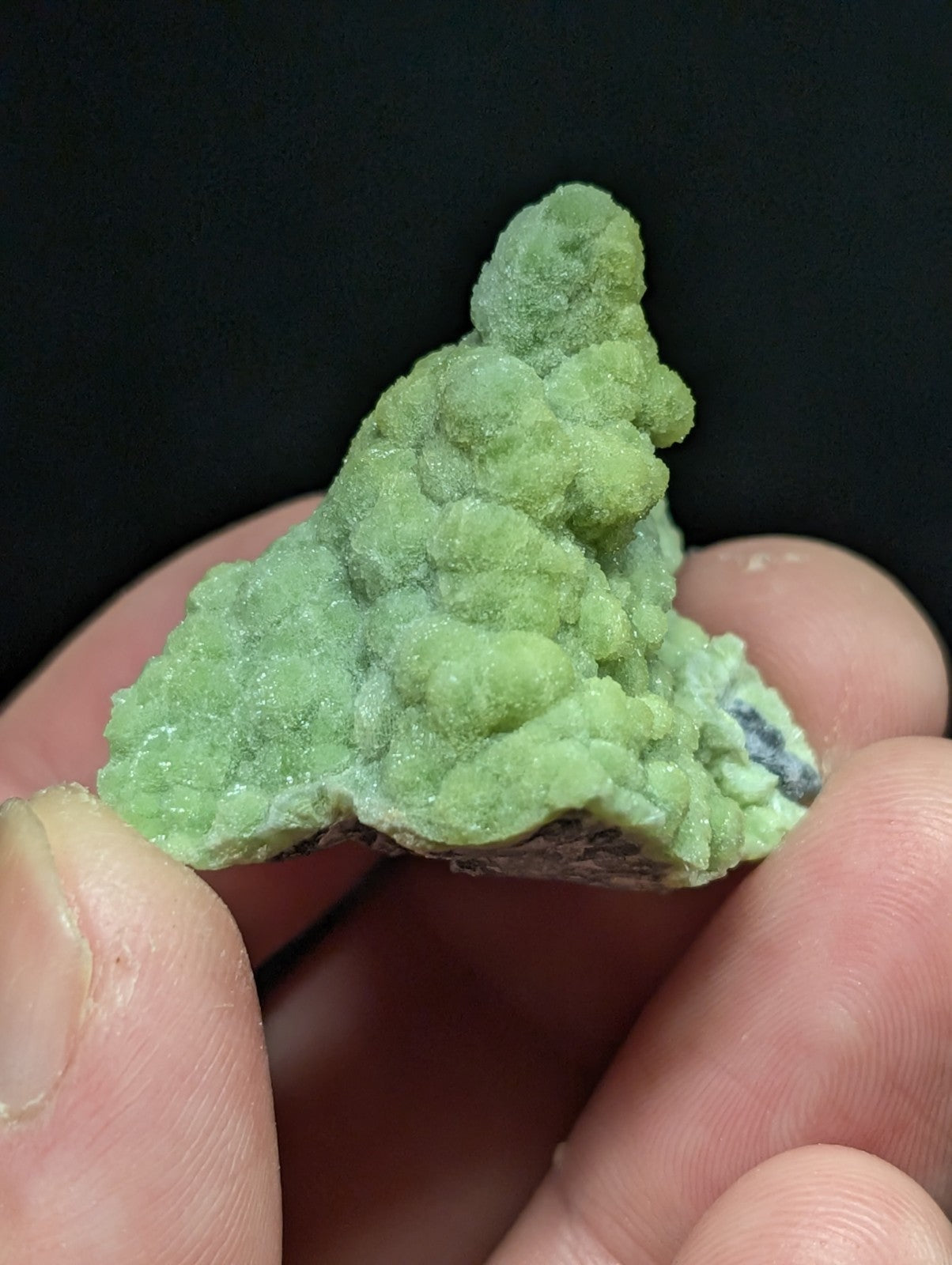 A textured, light green mineral specimen with a rough, crystalline surface and subtle hints of darker veining.