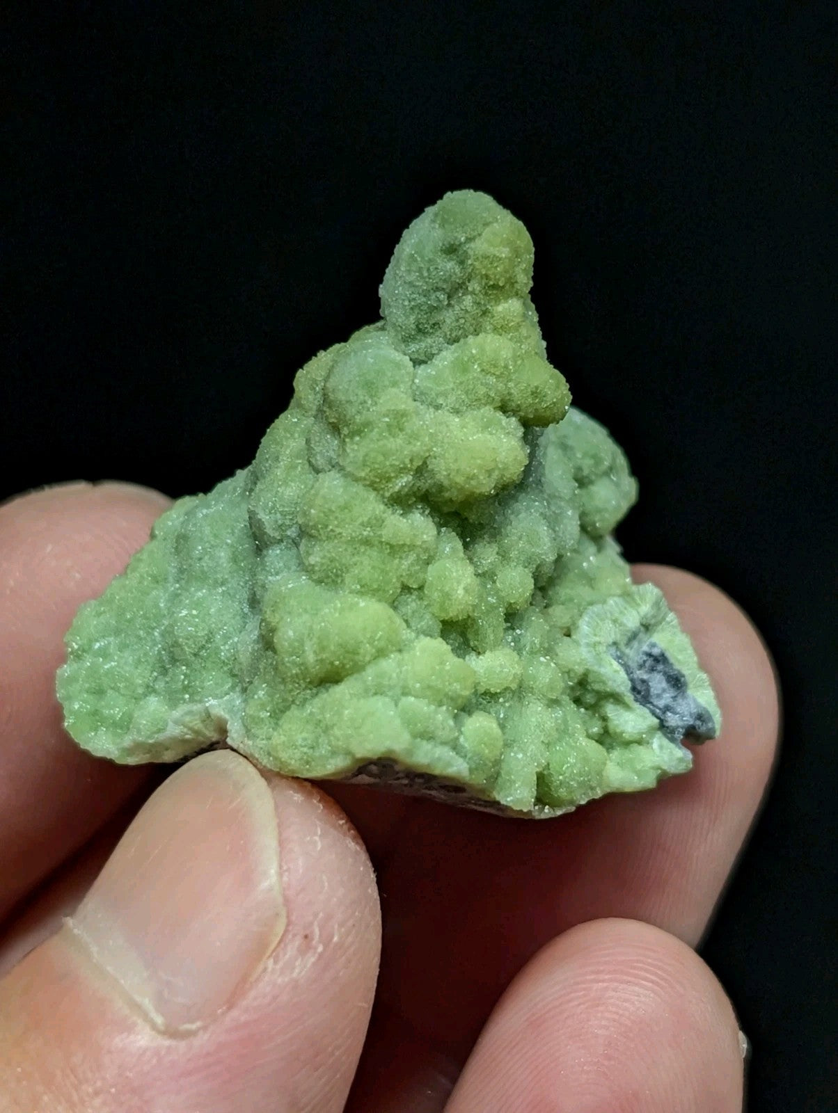 A vibrant green, textured mineral specimen with a rough, crystalline surface and small nodules.