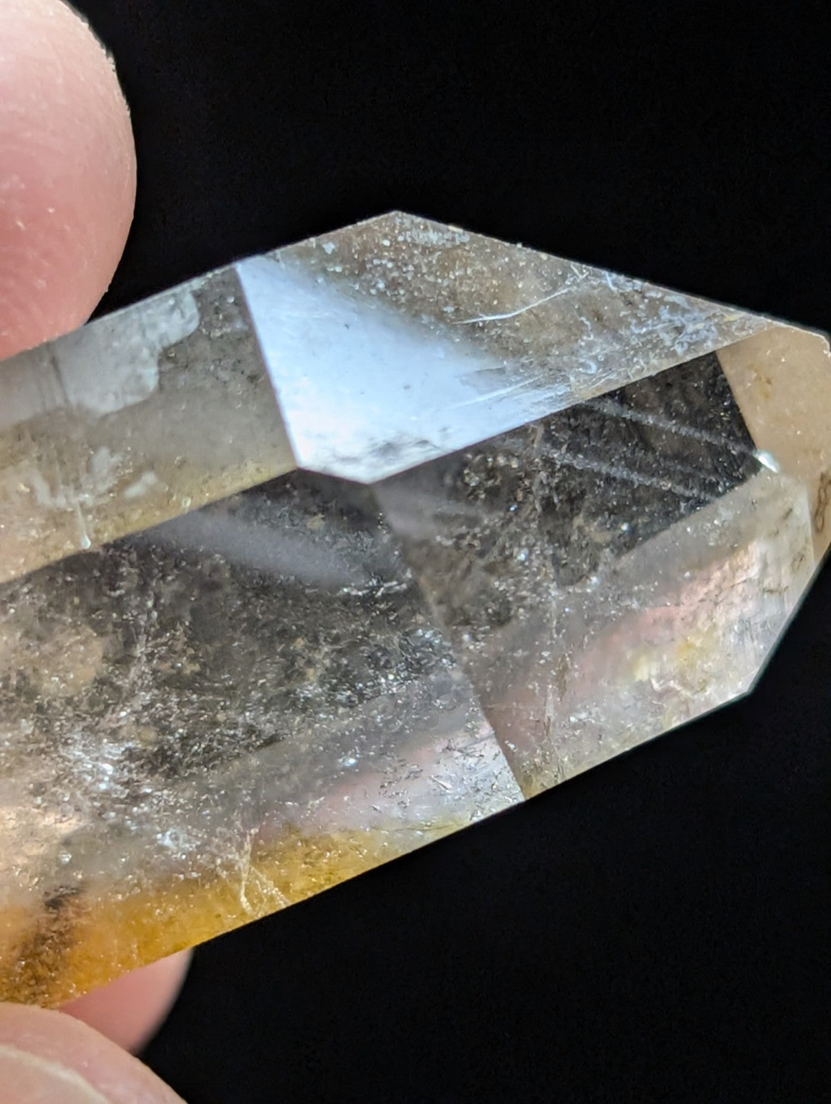 A translucent yellowish quartz crystal with a faceted, pointed tip and visible internal inclusions.