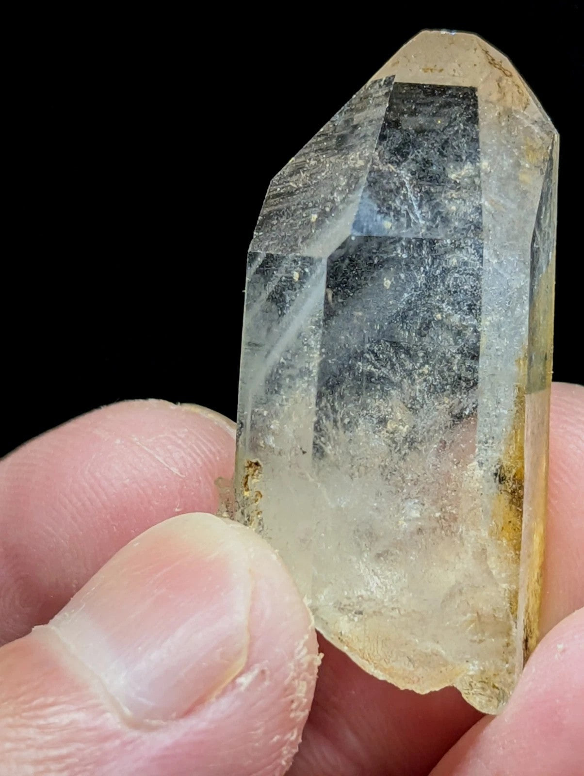 A translucent, pale yellowish quartz crystal with a pointed tip and visible internal inclusions.