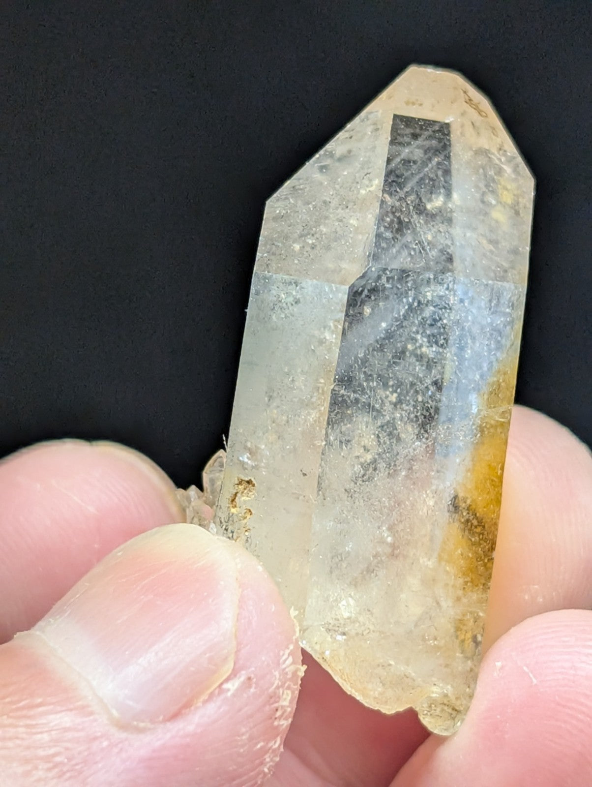 A translucent, pale yellow quartz crystal with a pointed tip and visible internal inclusions.