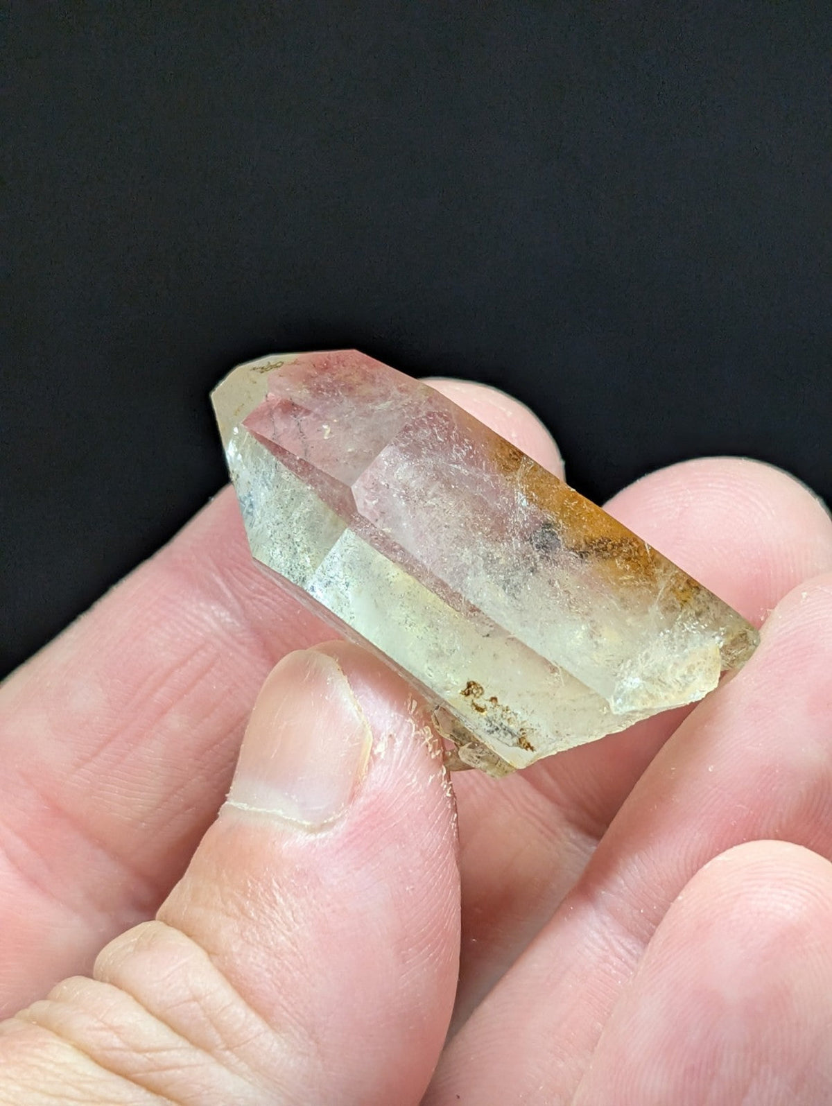 A translucent, pale yellowish crystal with subtle amber inclusions and a faceted, pointed top.