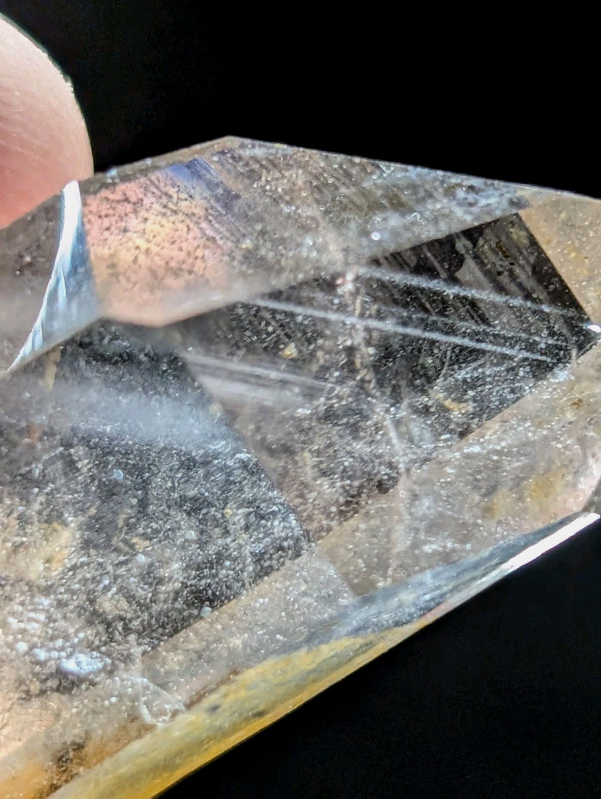 A translucent, faceted quartz crystal with a clear and cloudy interior featuring dark inclusions.