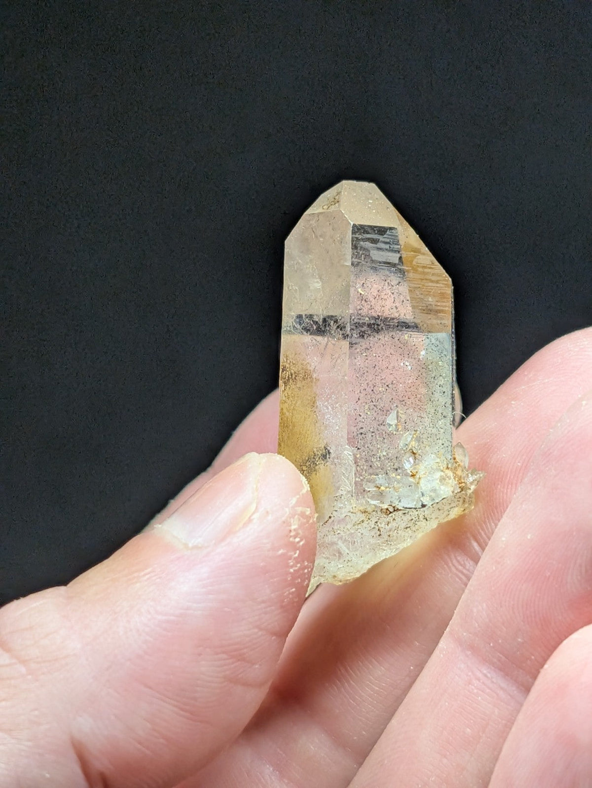 A translucent yellowish quartz crystal with natural inclusions and a pointed, faceted tip.