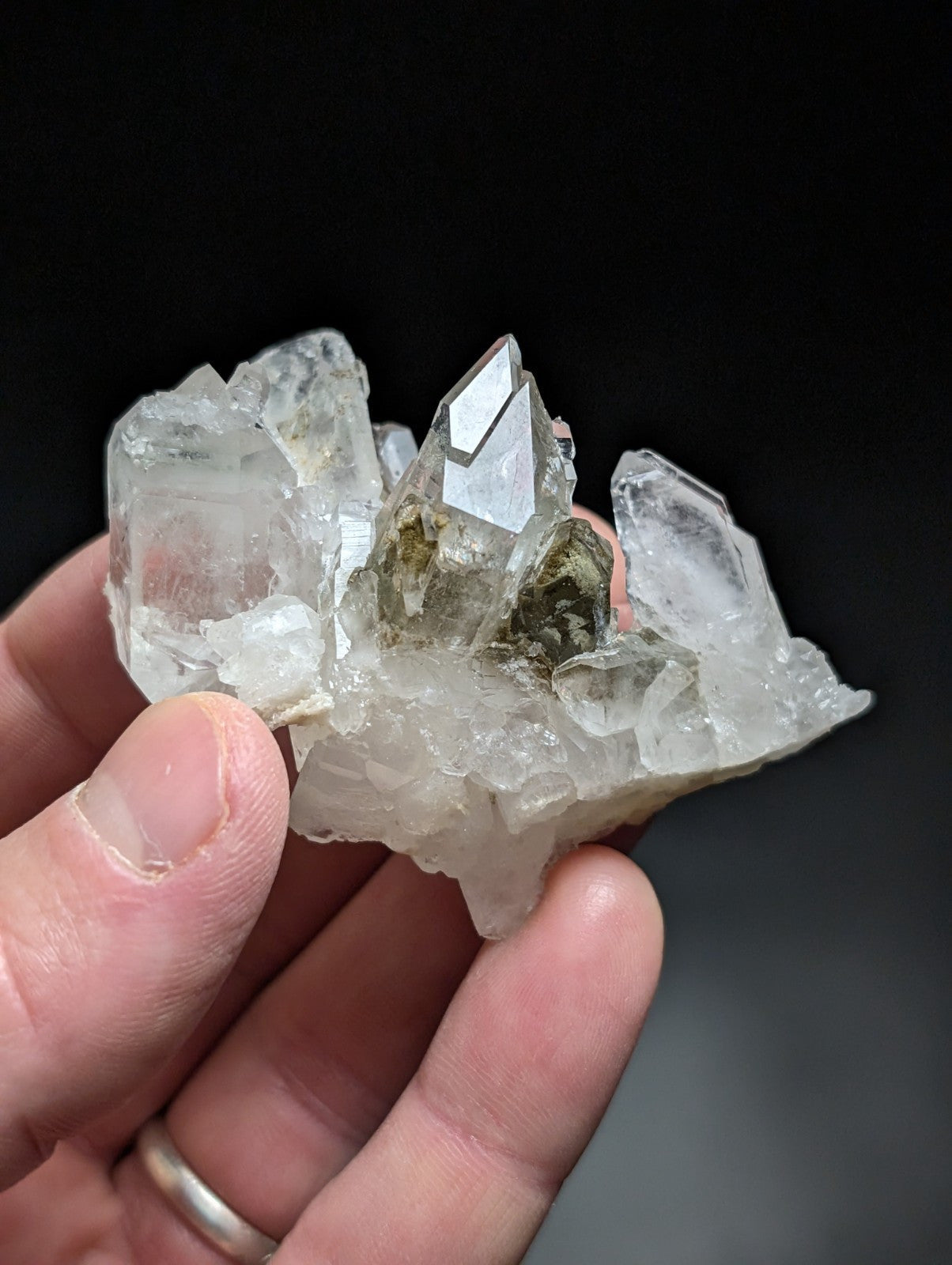 A translucent quartz crystal cluster with sharp, faceted points and a central greenish inclusion.