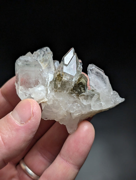 A translucent quartz crystal cluster with sharp, faceted points and a central greenish inclusion.