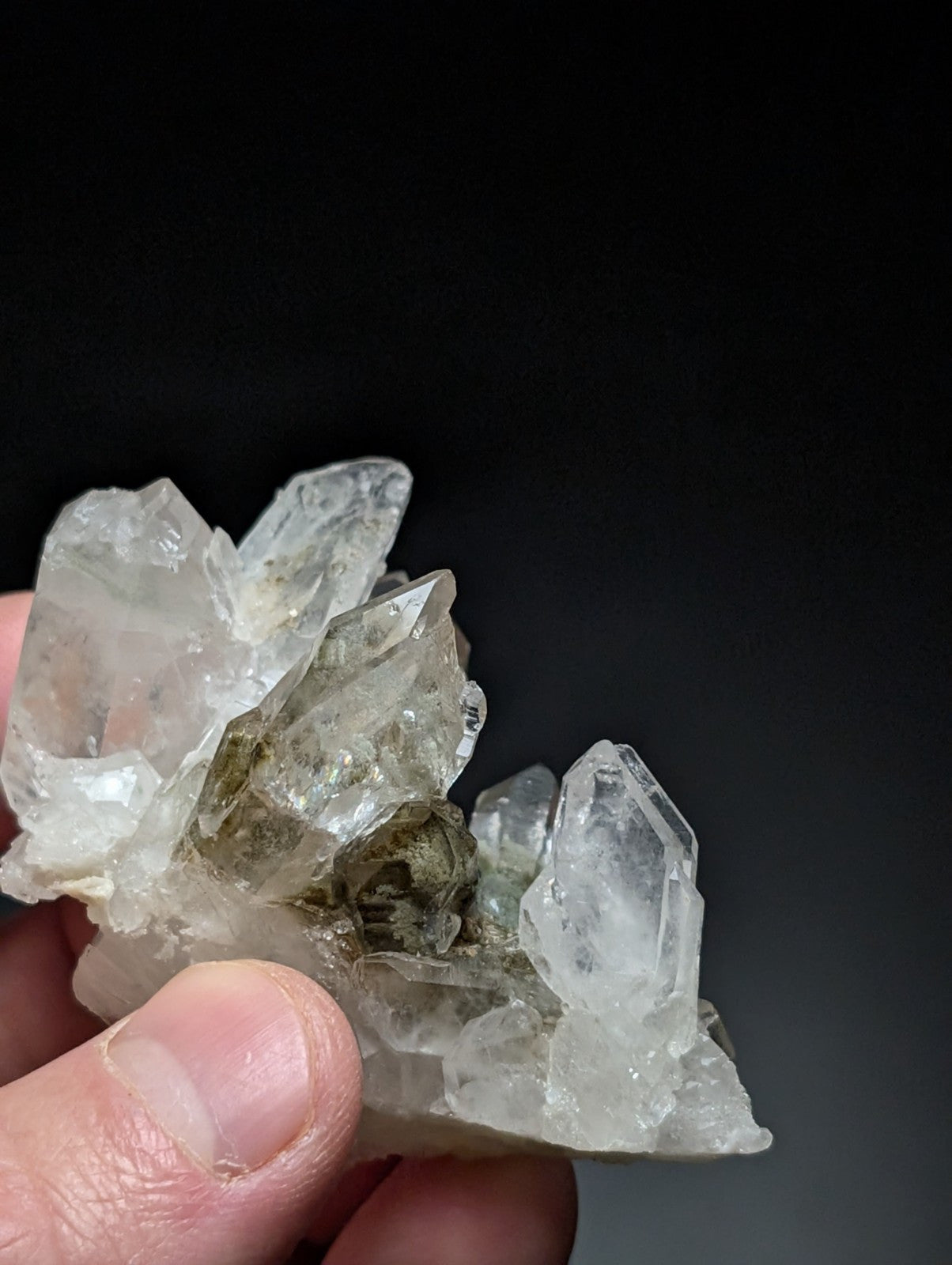 A cluster of clear, translucent quartz crystals with some exhibiting a faint greenish tint and rough, jagged edges.