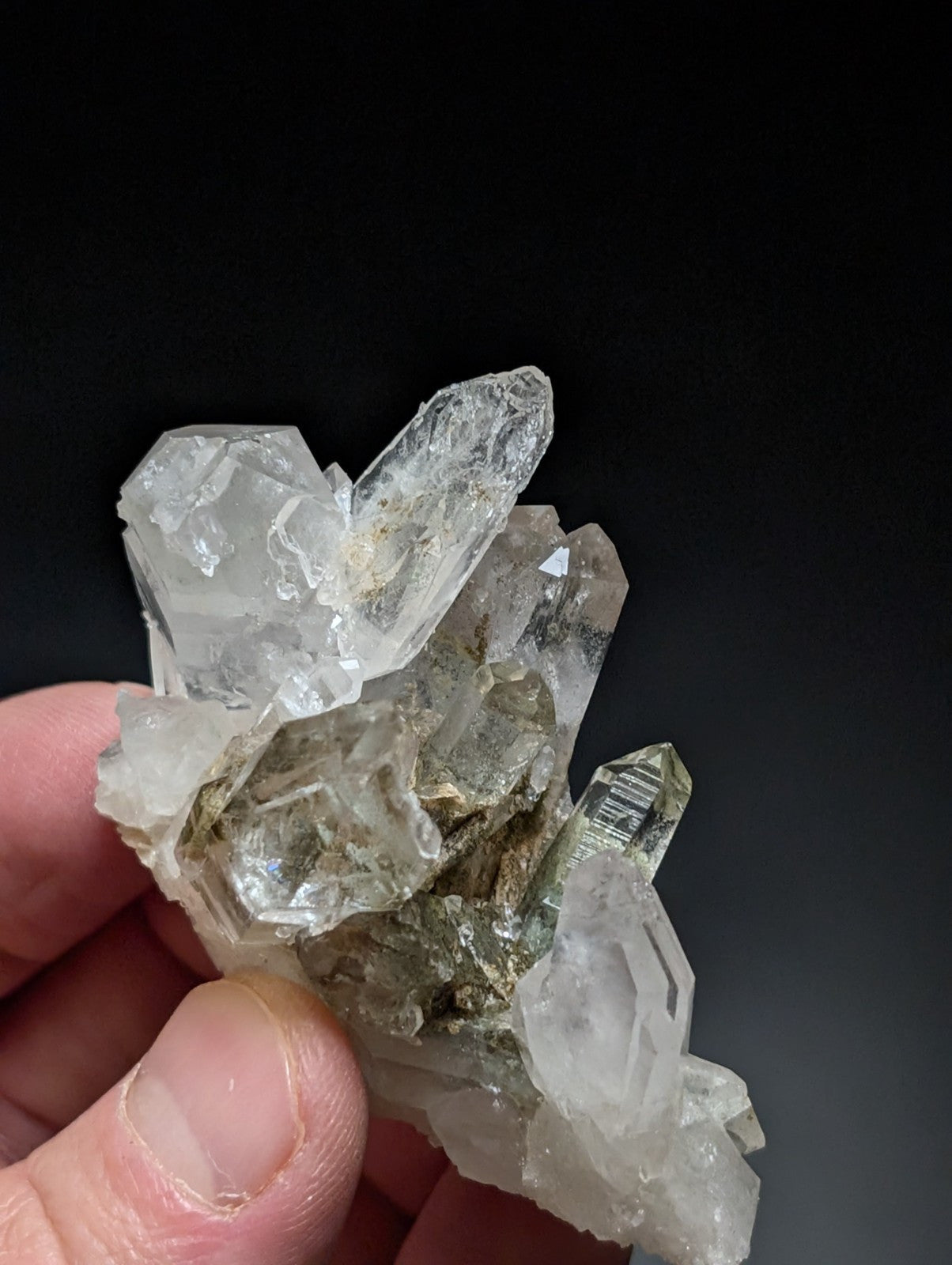 A cluster of clear, translucent quartz crystals with sharp facets and subtle greenish tints.