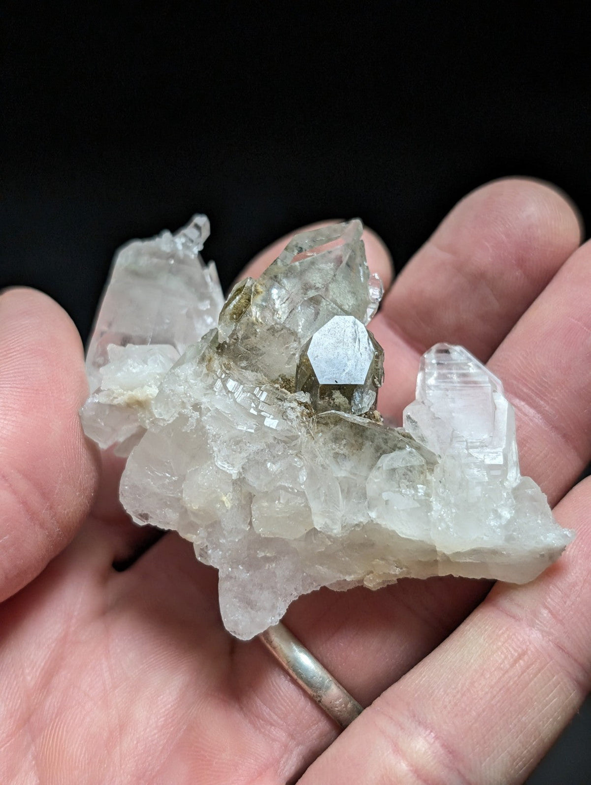 A translucent, clear quartz crystal cluster with a central hexagonal gemstone and jagged edges.