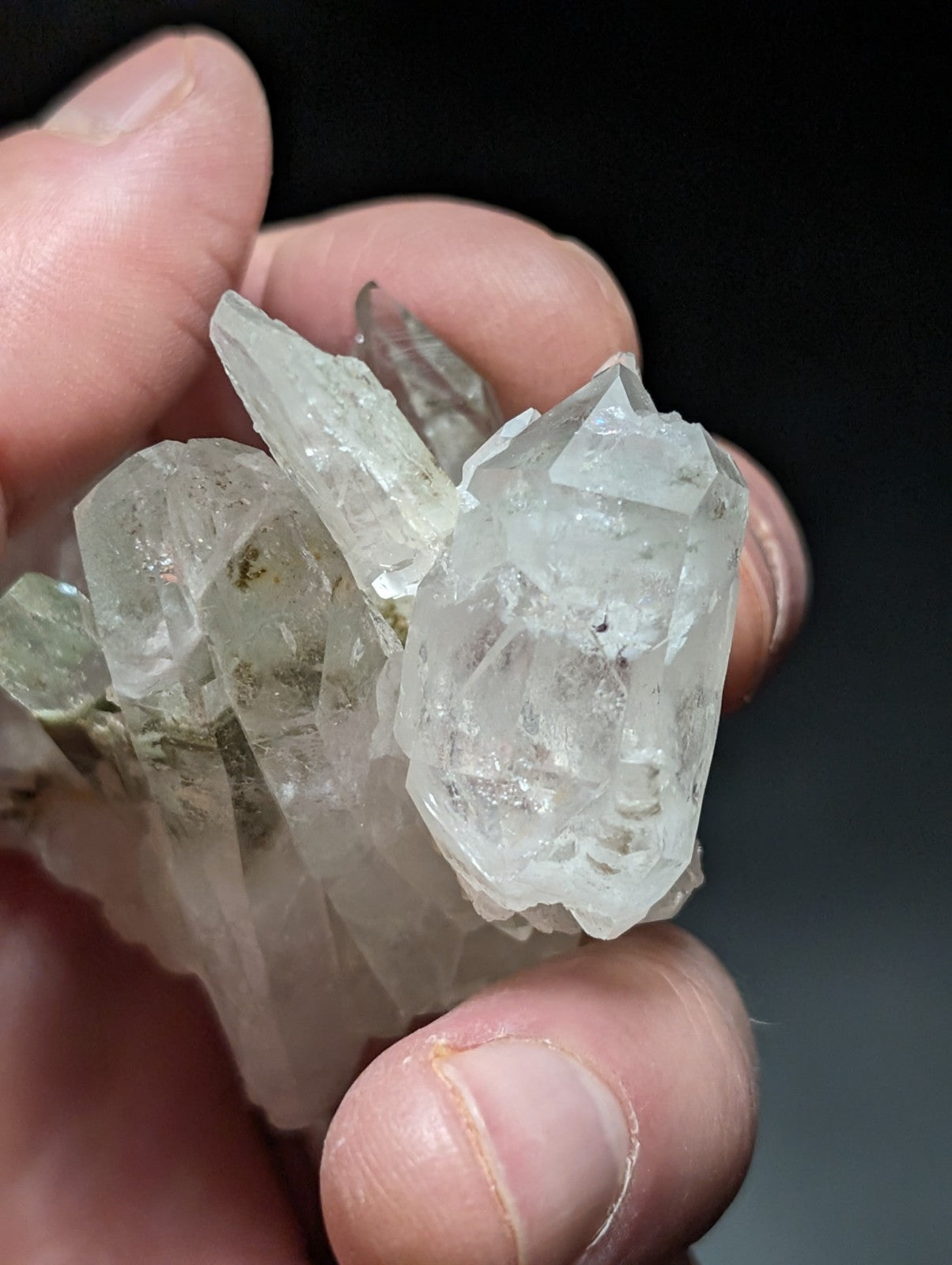 A translucent, clear quartz crystal cluster with sharp facets and subtle greenish inclusions.