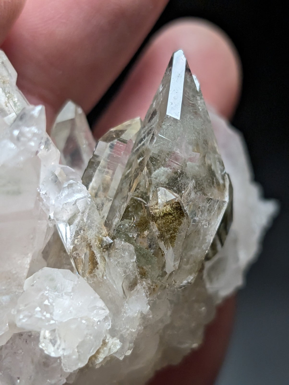 A clear quartz crystal cluster with sharp, faceted points and subtle golden inclusions nestled among translucent white crystals.