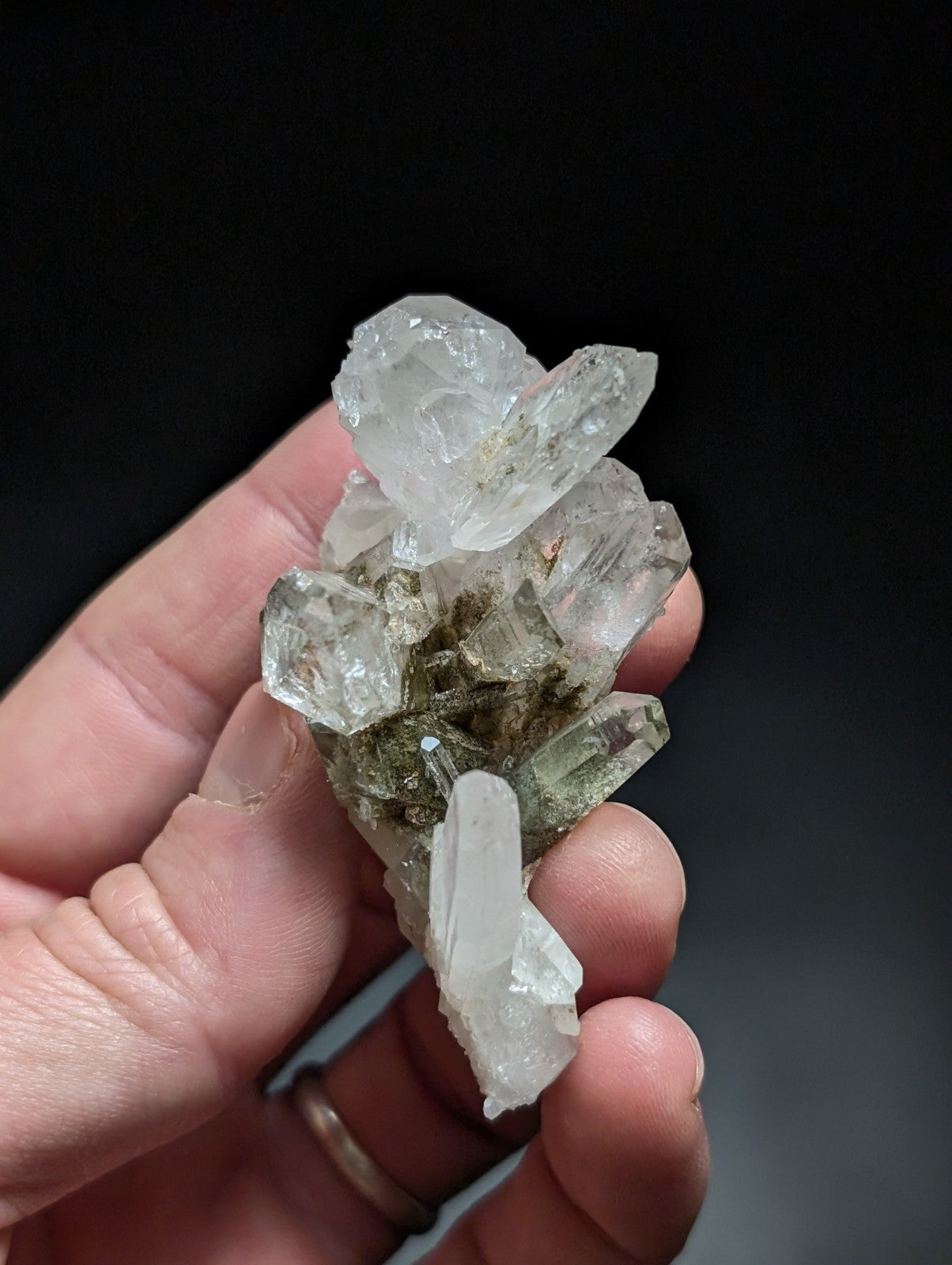 A cluster of clear, translucent quartz crystals with some exhibiting a faint greenish tint and rough, jagged edges.