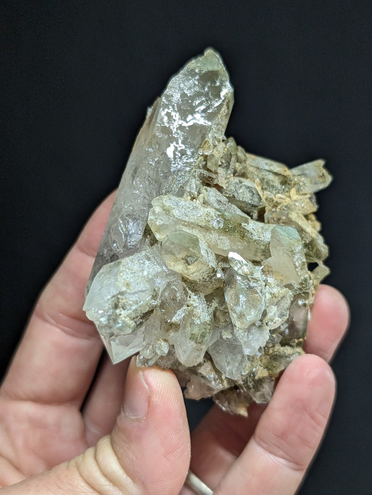 A translucent, pale green quartz crystal cluster with sharp facets and a rough, earthy base.