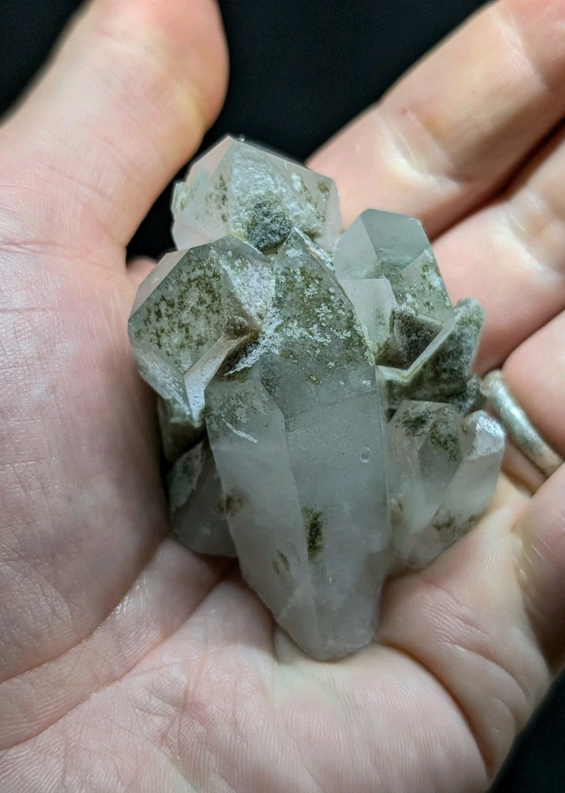 A translucent, pale gray quartz crystal cluster with natural greenish inclusions and sharp geometric facets.