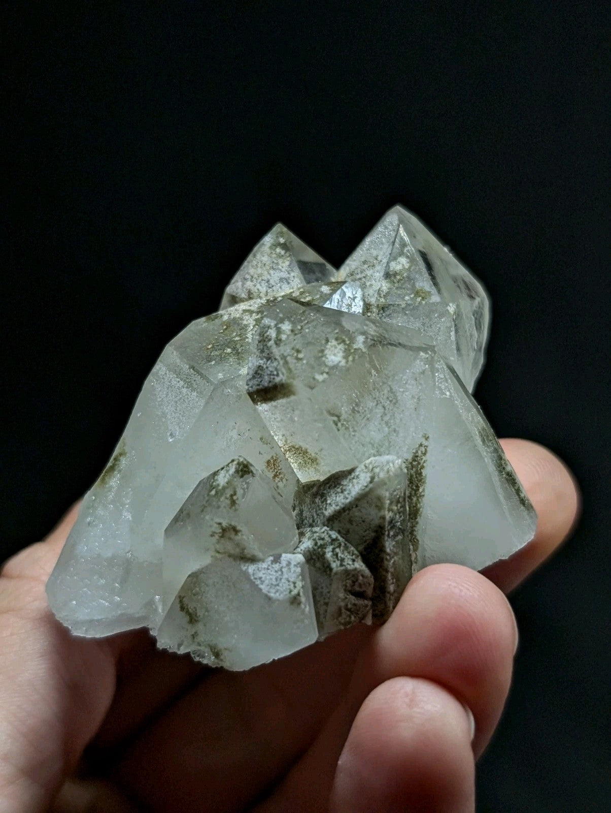 A translucent quartz crystal cluster with pointed, faceted formations and subtle greenish inclusions.
