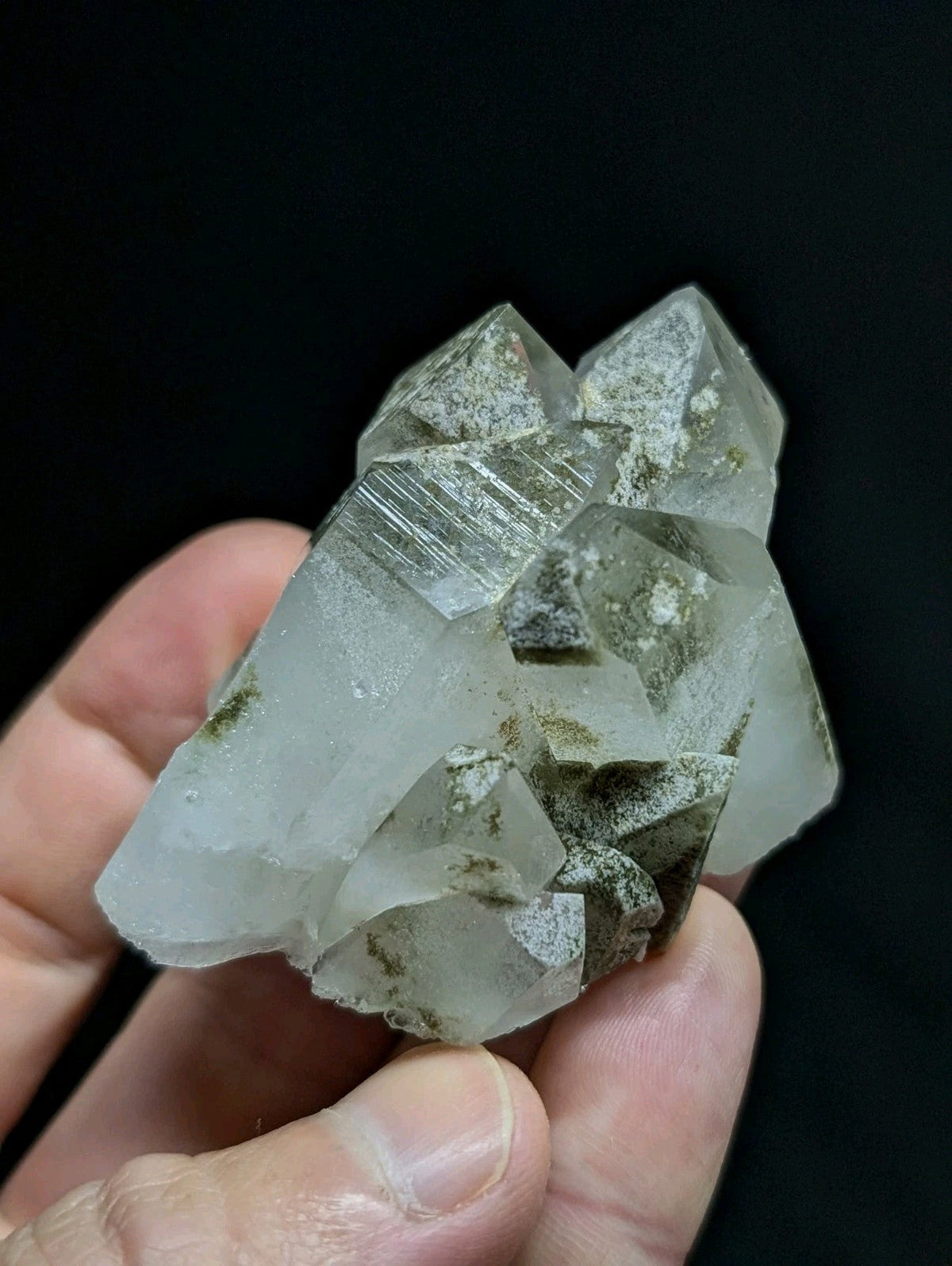 A translucent, pale quartz crystal cluster with sharp geometric facets and subtle greenish mineral inclusions.