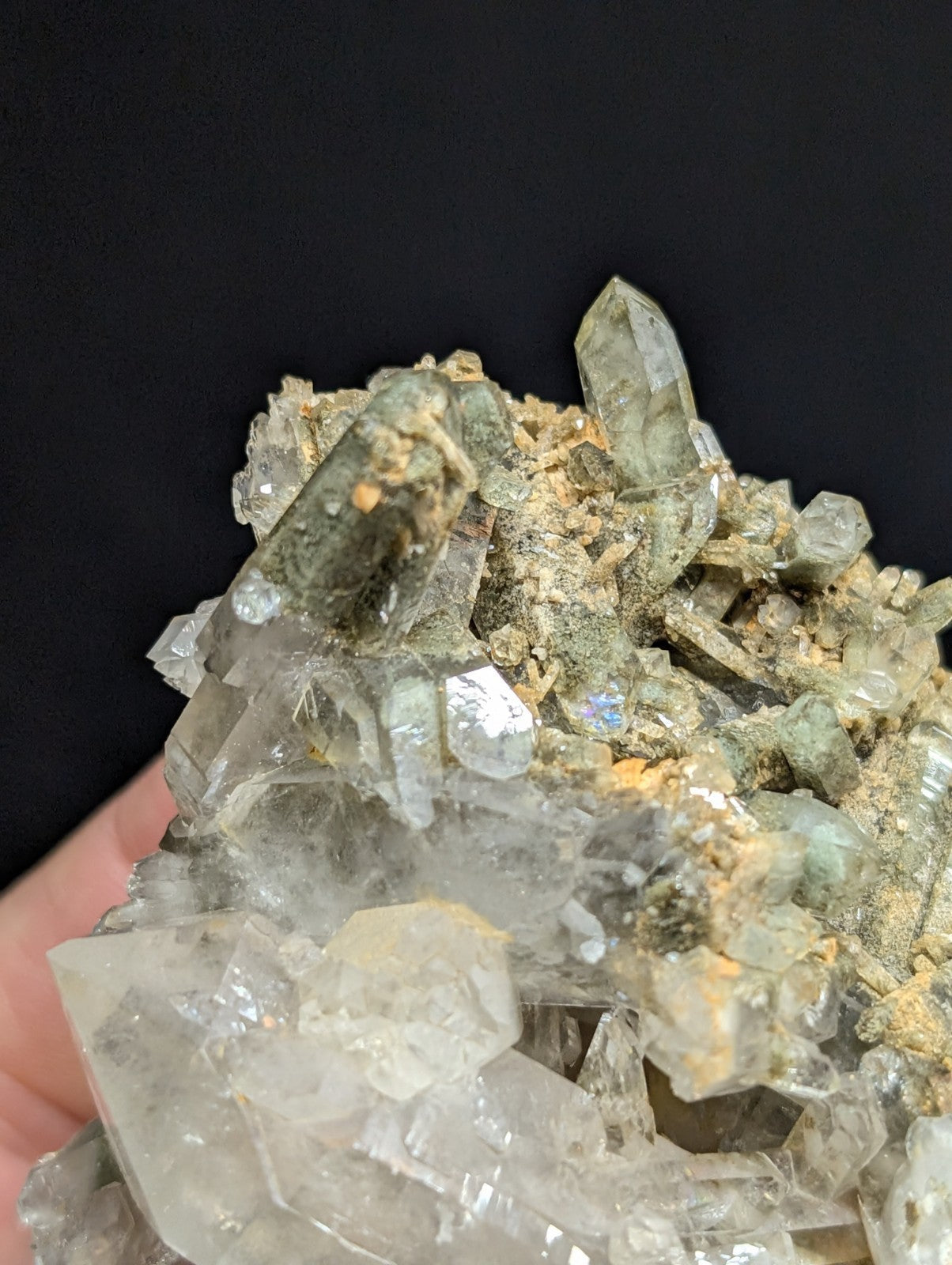 A cluster of translucent quartz crystals with greenish and clear facets, embedded in a rough matrix.