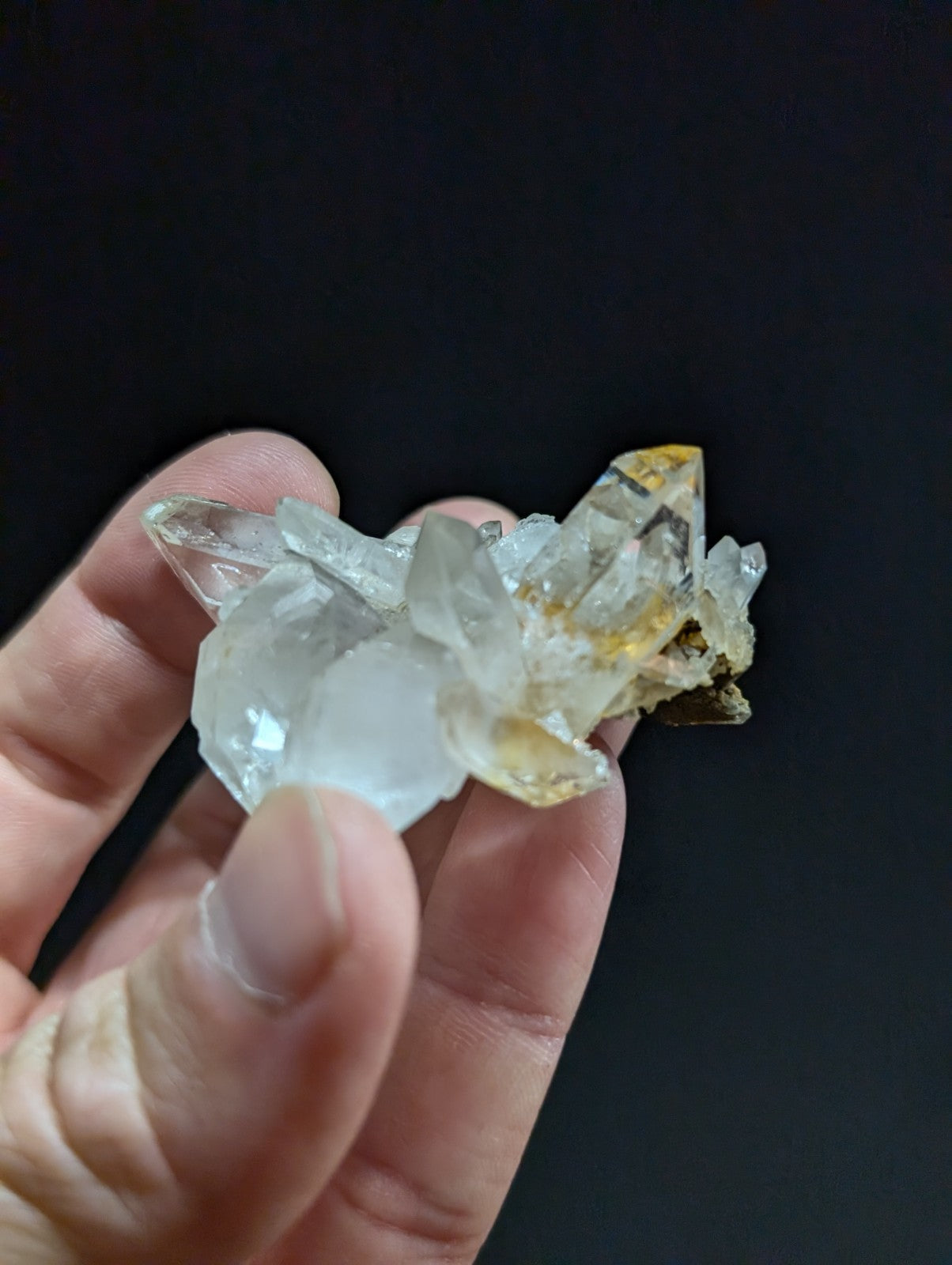 A translucent quartz crystal cluster with clear, faceted points and subtle golden-yellow inclusions.