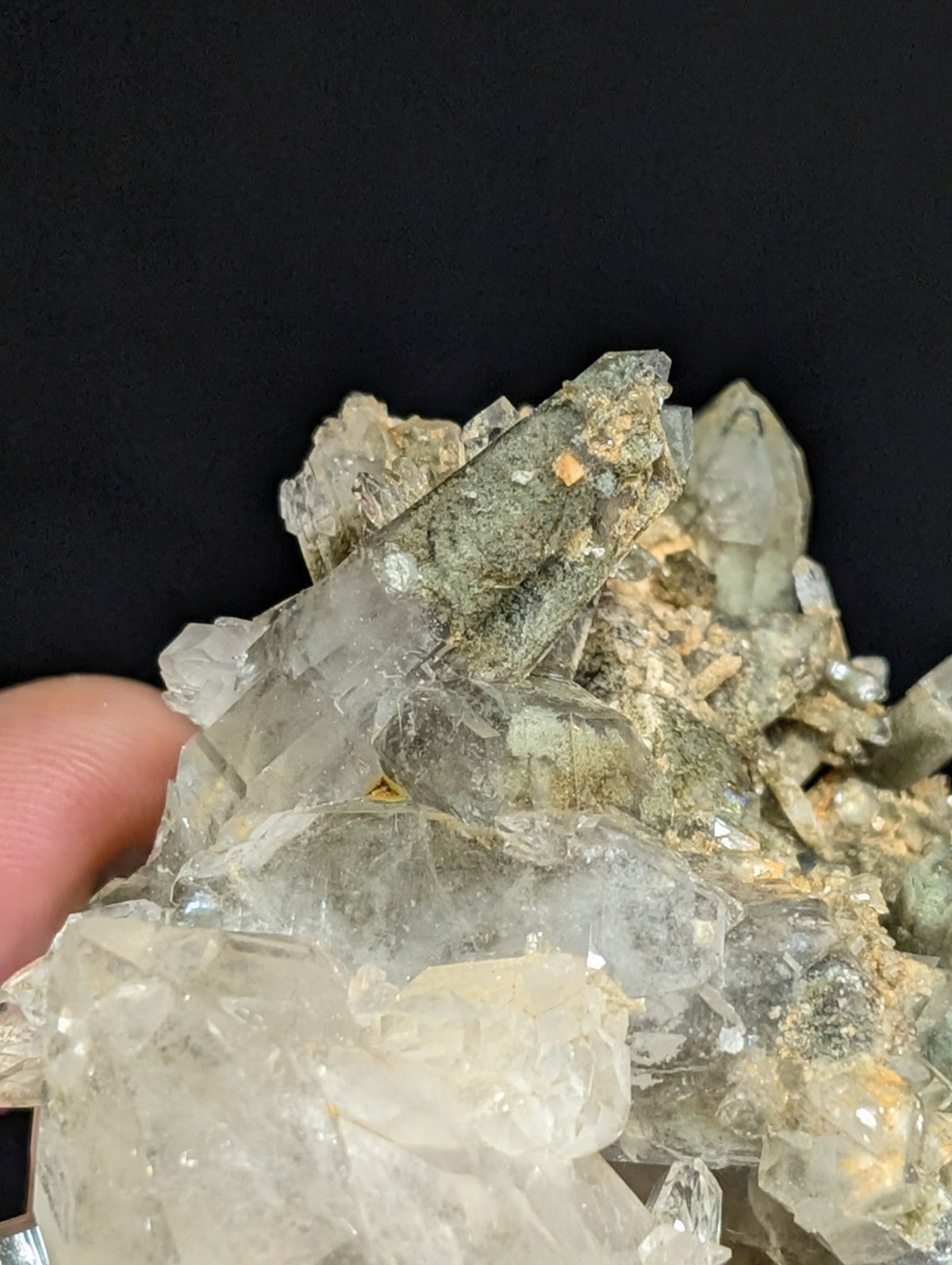 A cluster of translucent quartz crystals with greenish and yellowish mineral inclusions, forming a natural geode specimen.