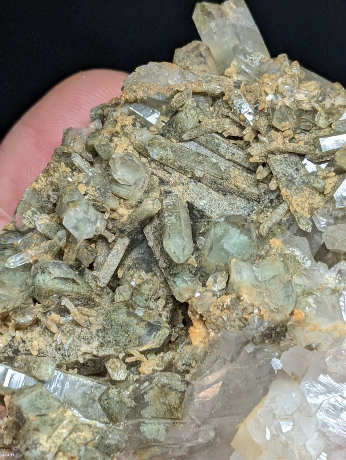 A cluster of translucent green and clear quartz crystals with earthy yellowish matrix.