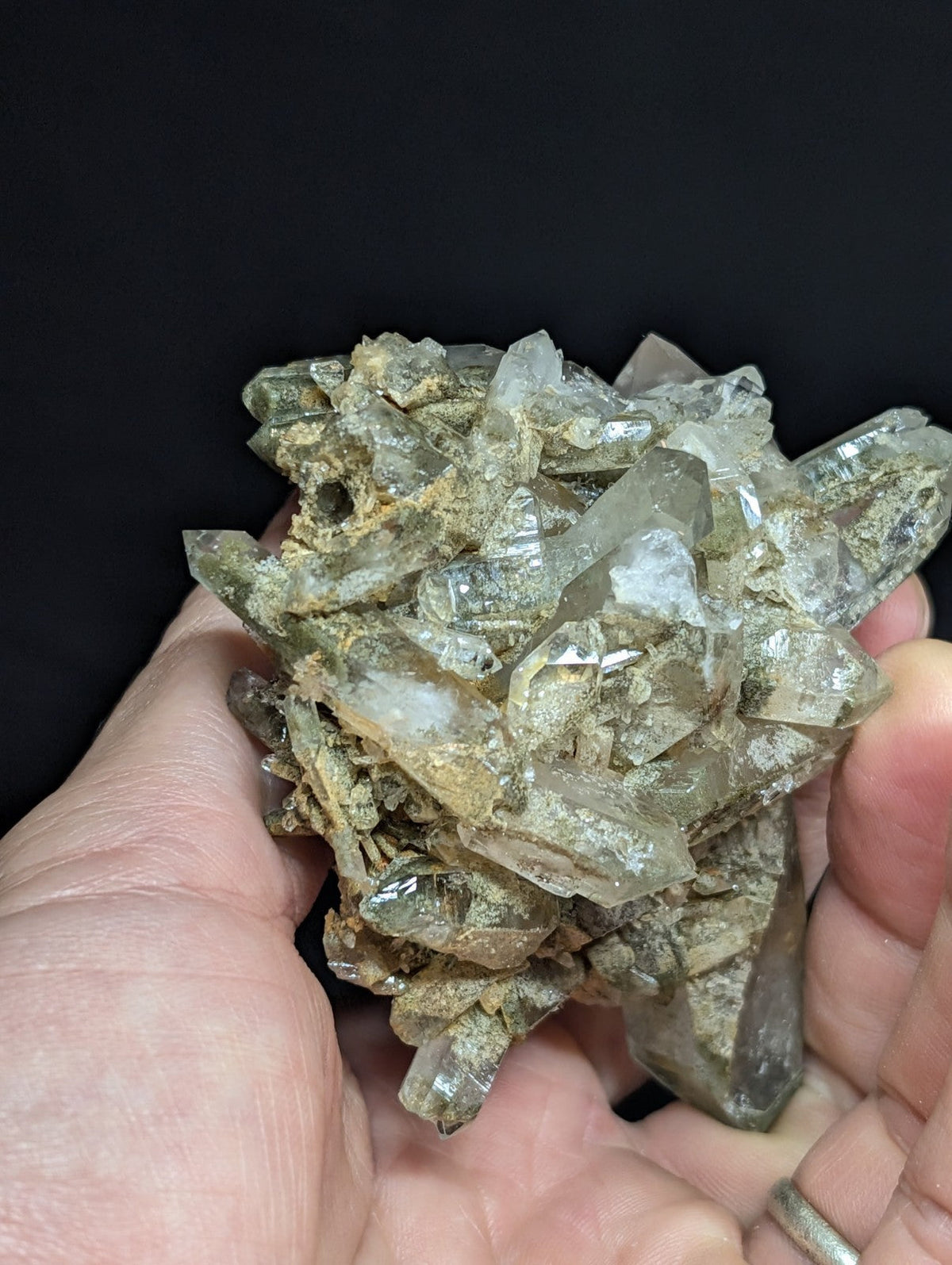 A cluster of translucent, clear quartz crystals with earthy brown and gray veining.