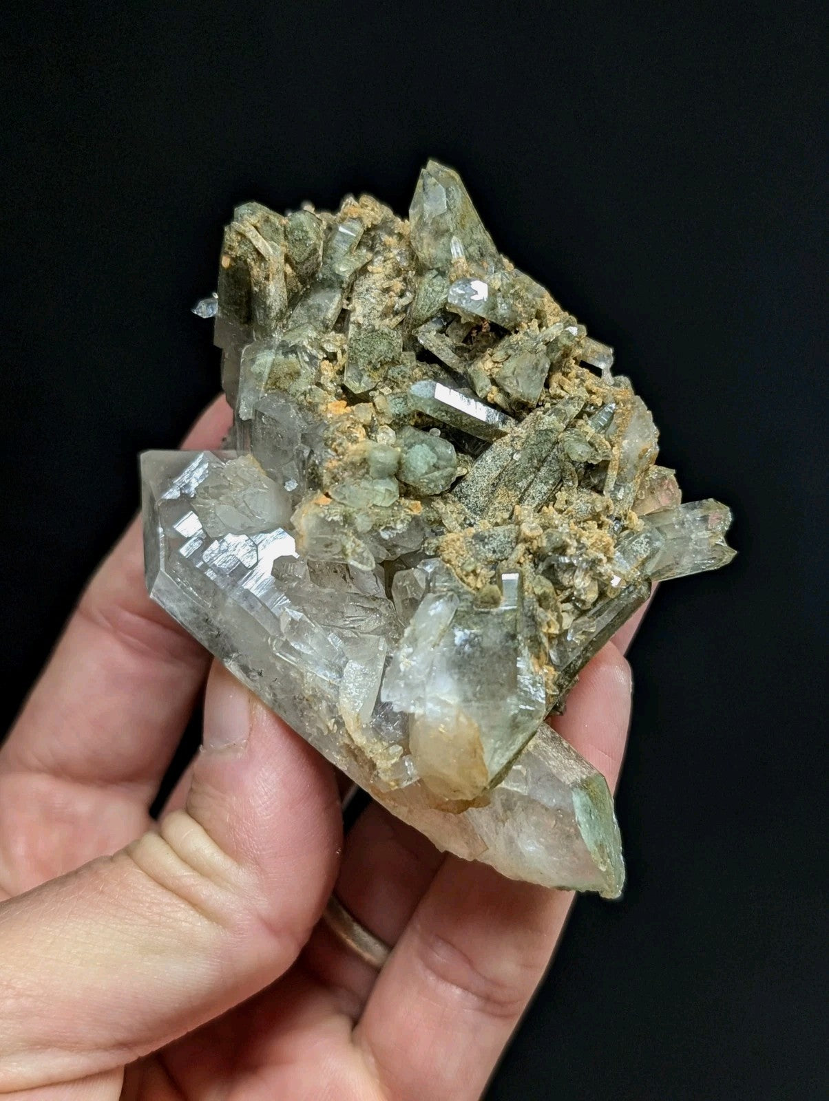 A translucent greenish quartz crystal cluster with sharp, faceted points and embedded earthy matrix.