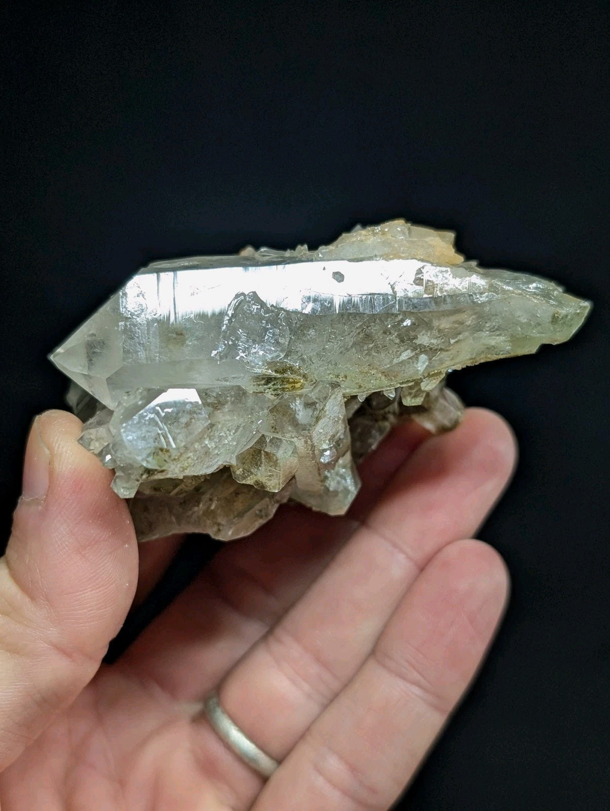 A translucent, pale green quartz crystal cluster with a pointed tip and rough, jagged edges.