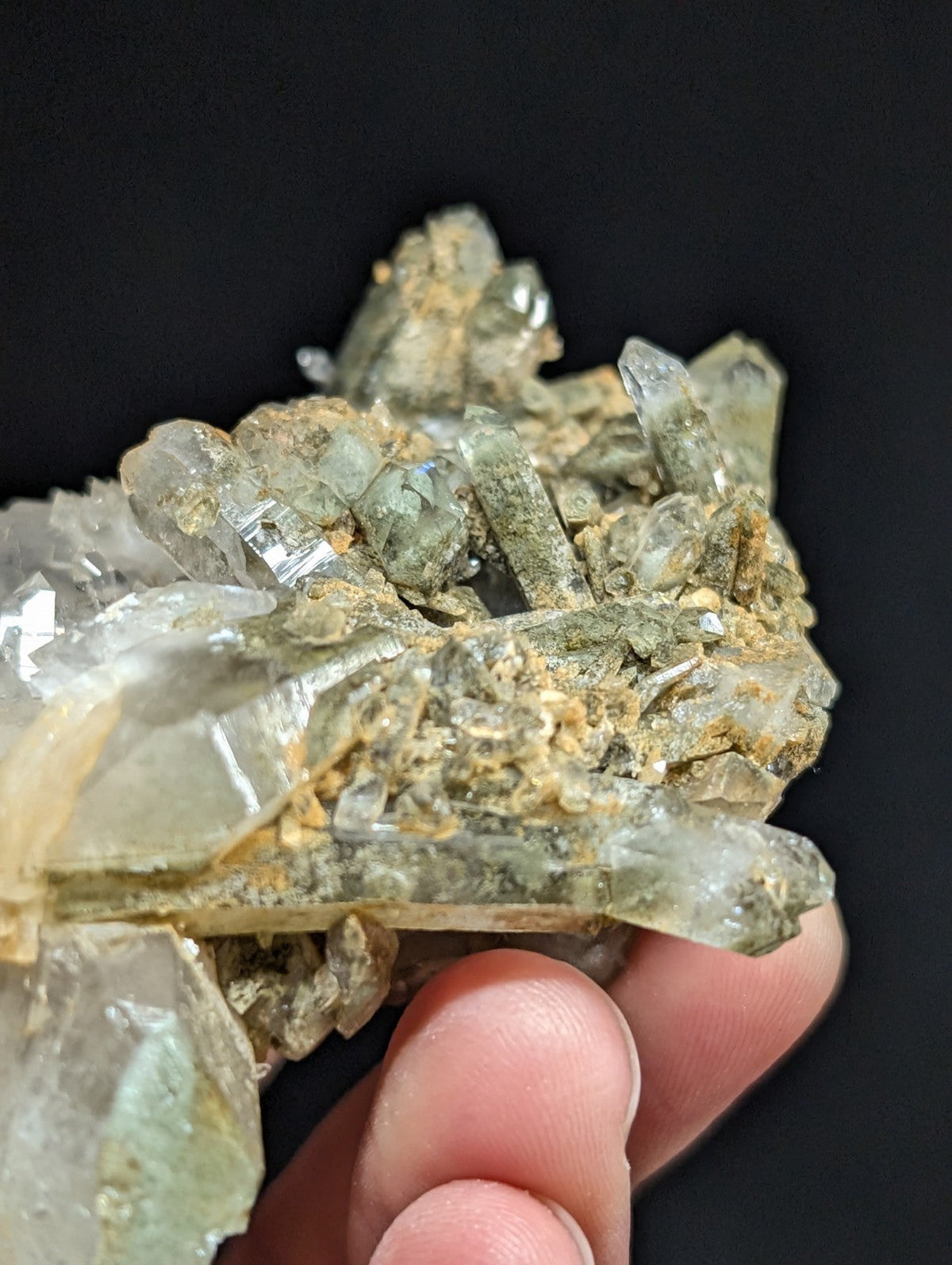 A cluster of translucent green and clear quartz crystals with earthy matrix.