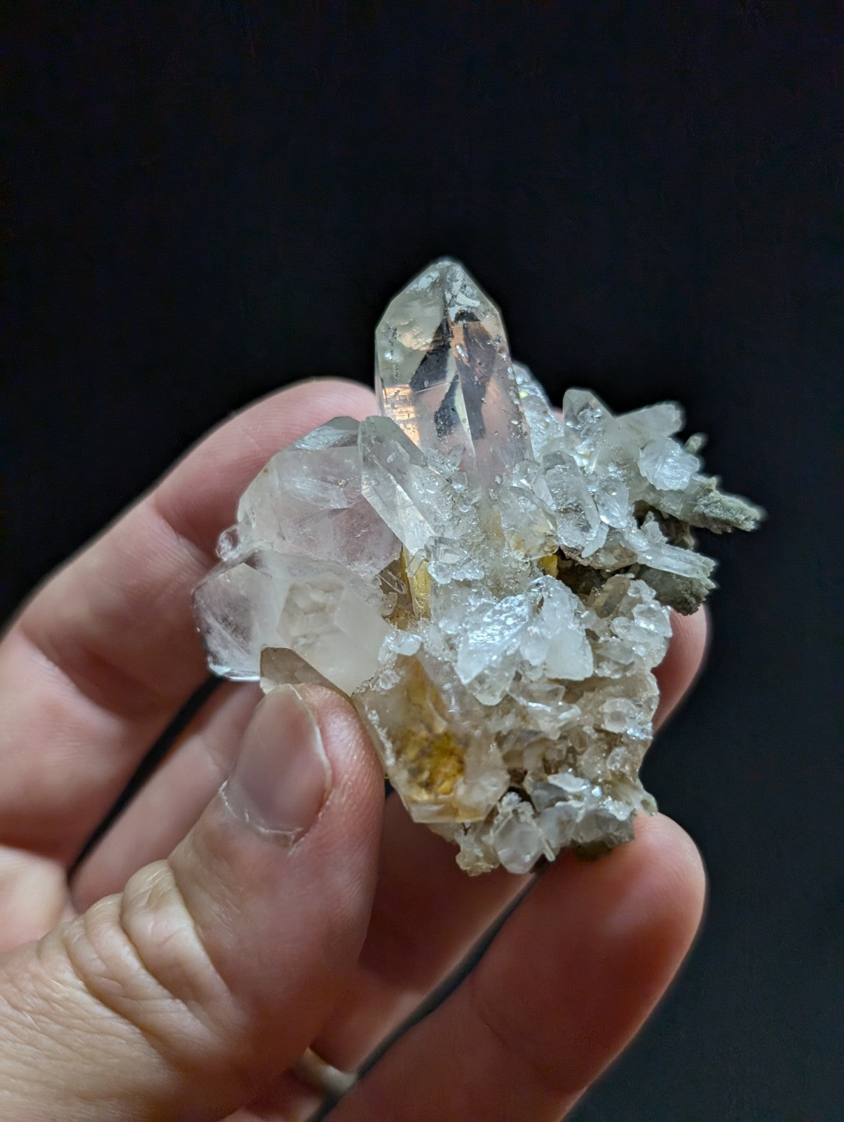 A translucent, clear quartz crystal cluster with sharp facets and subtle golden inclusions.