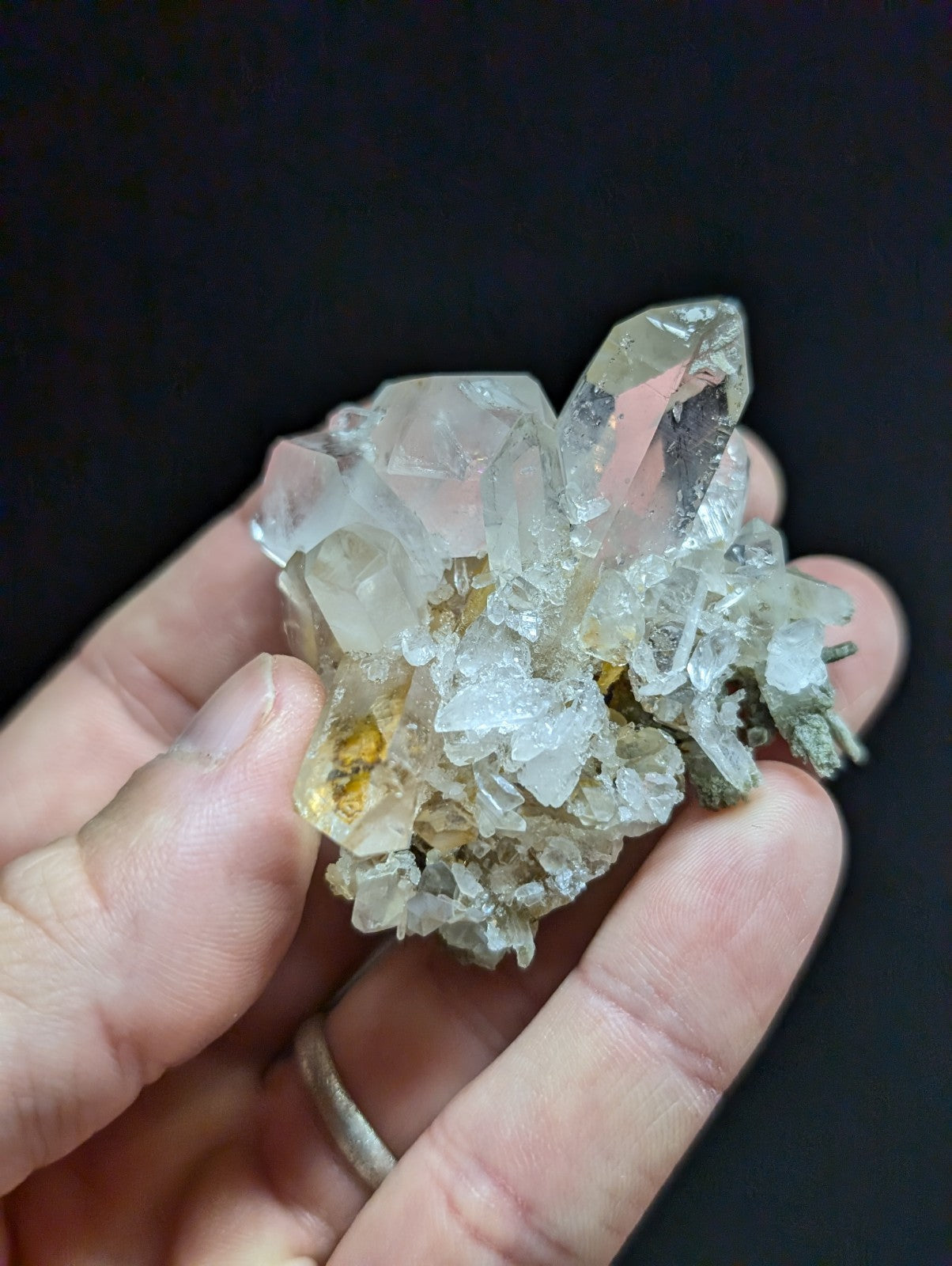 A translucent, clear quartz crystal cluster with subtle golden and gray inclusions.