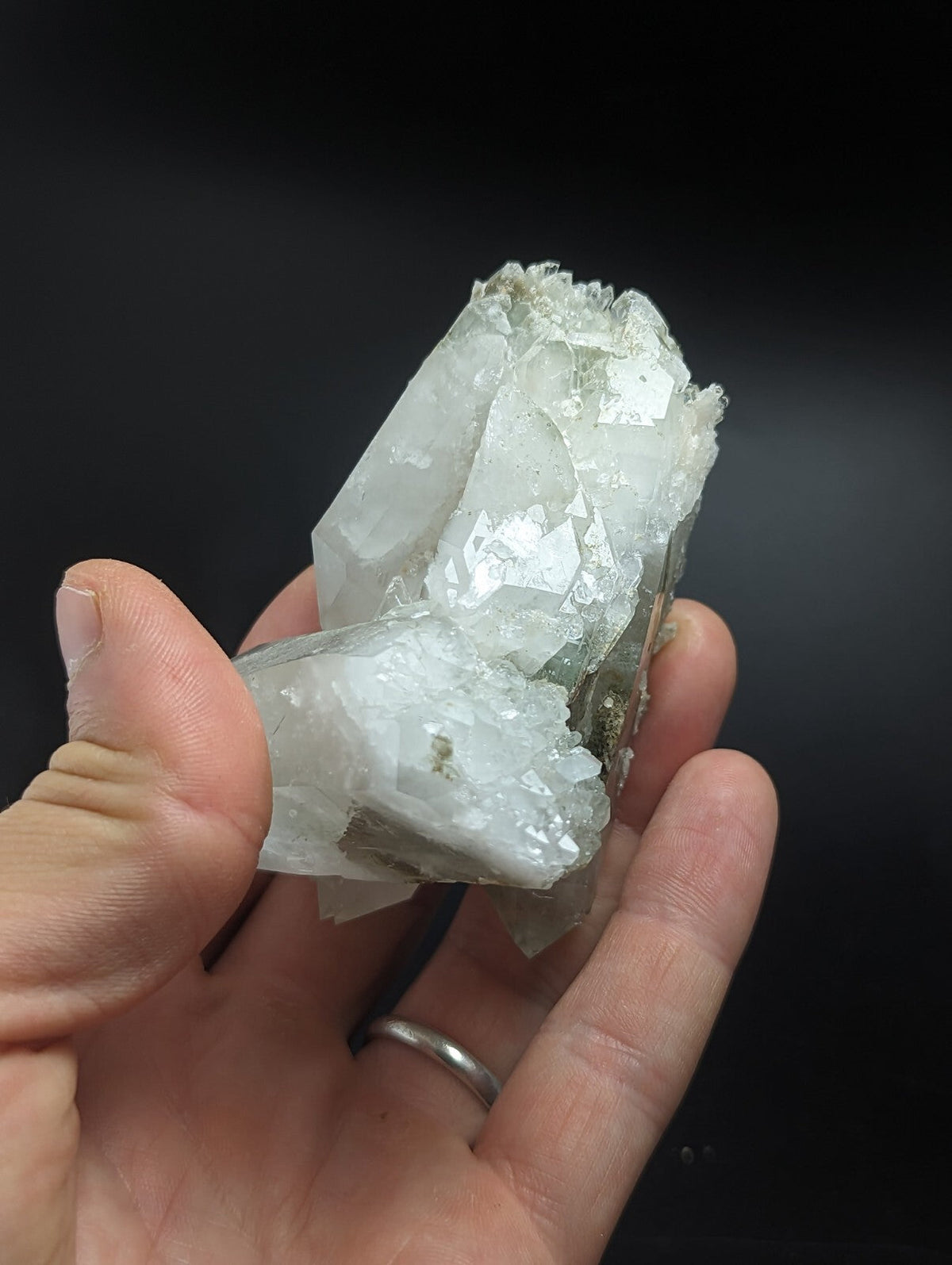 A translucent white quartz crystal cluster with sharp, faceted edges and a slightly rough, mineral-rich base.