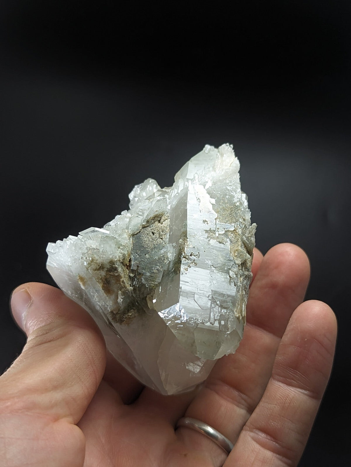 A translucent white quartz crystal cluster with sharp, faceted points and subtle greenish-gray mineral inclusions.