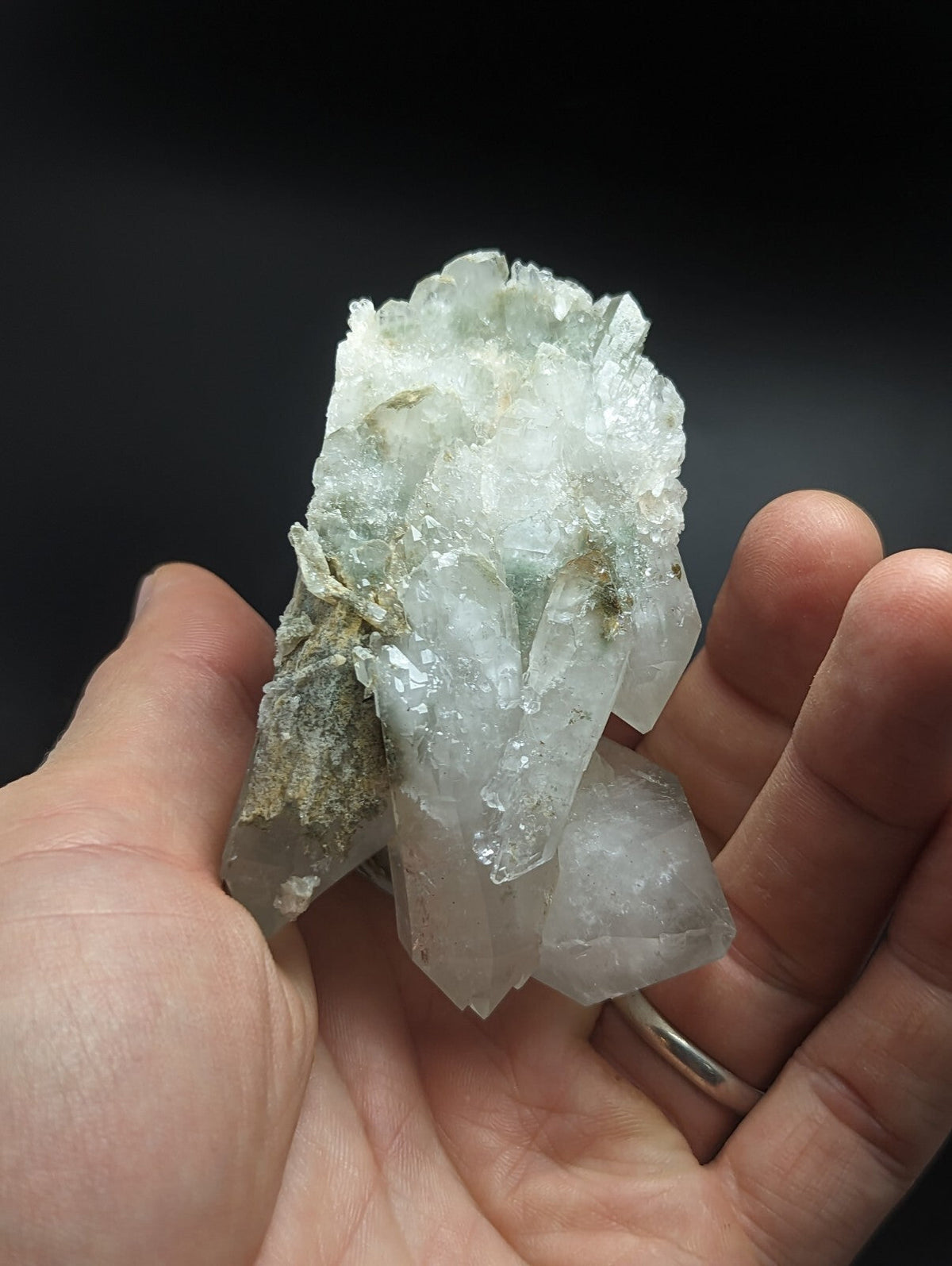 A translucent, pale greenish-white quartz crystal cluster with sharp, faceted points and some mineral inclusions.