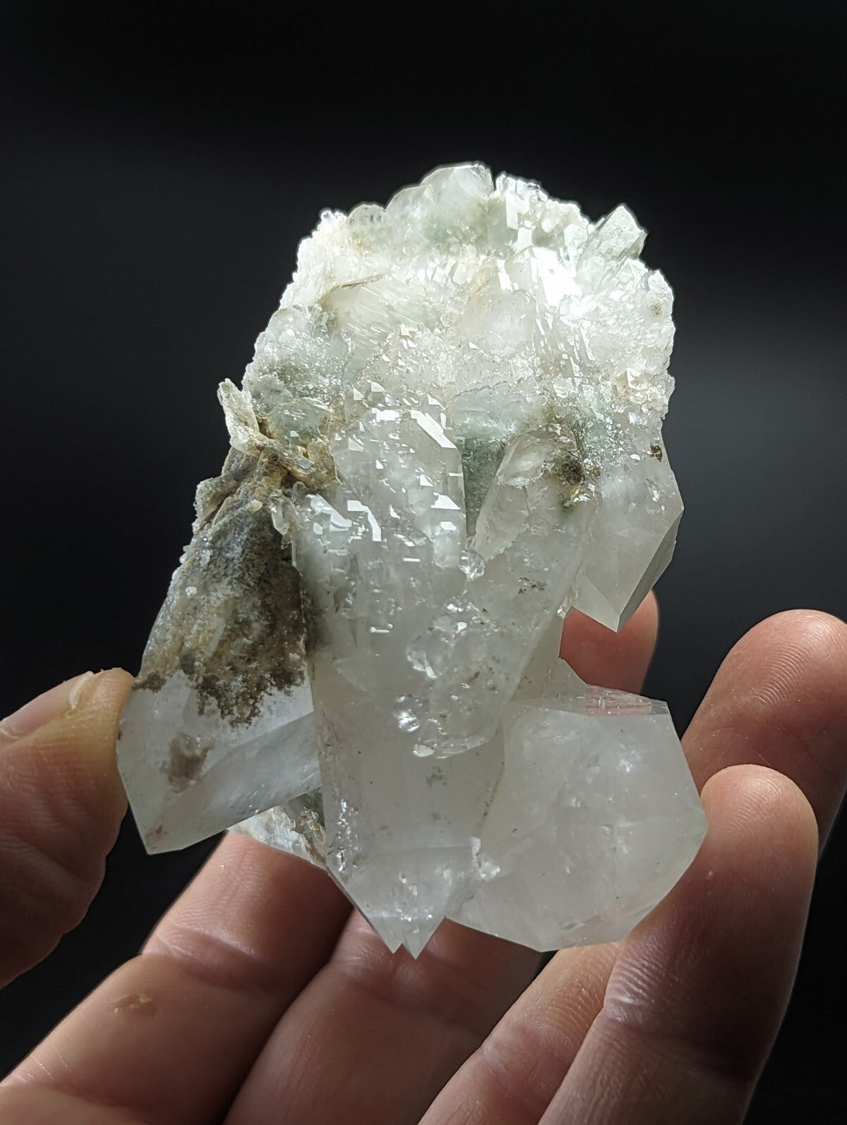 A translucent, pale green and white quartz crystal cluster with jagged edges and a rough, earthy base.