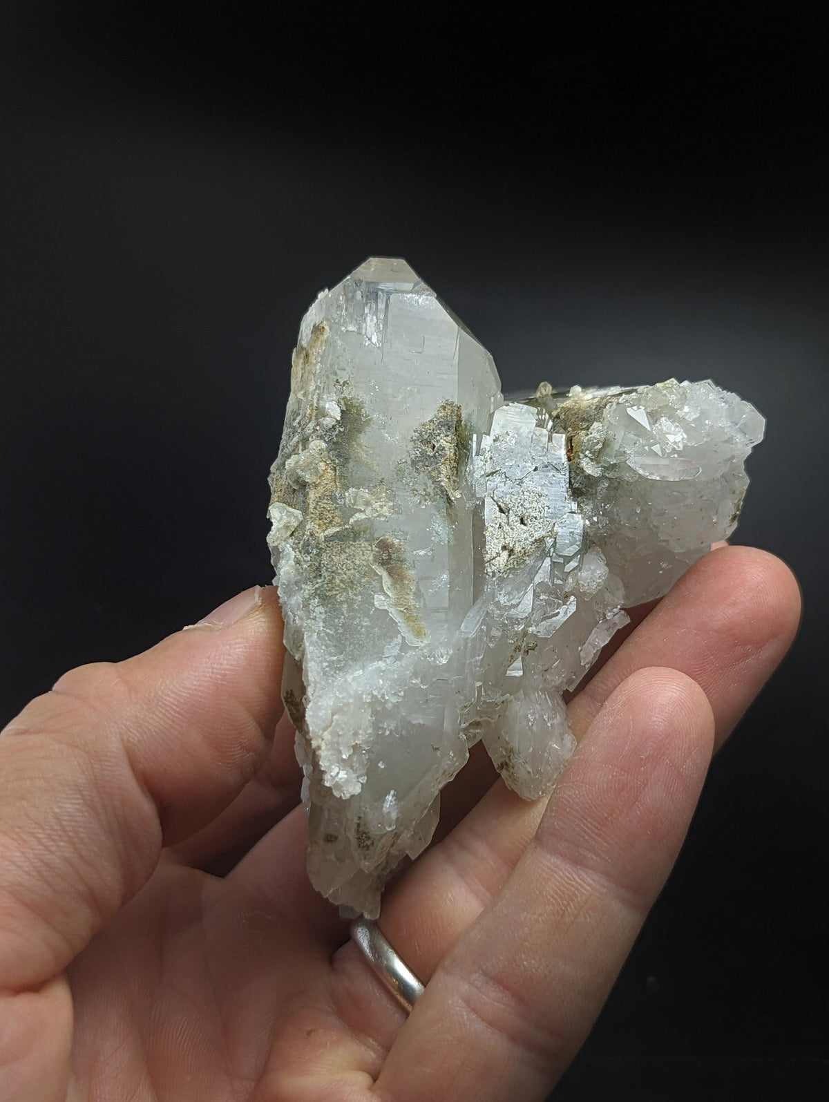 A translucent, pale quartz crystal cluster with visible greenish mineral inclusions and a rough, natural surface.