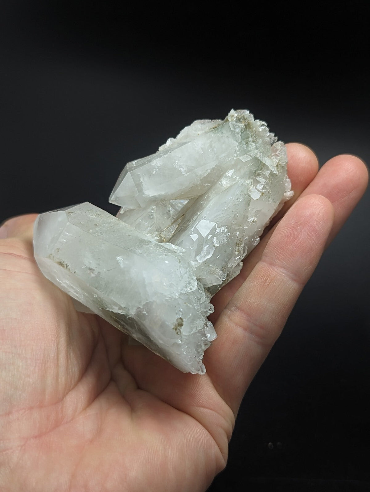 A translucent, pale greenish-white quartz crystal cluster with sharp facets and a rough, natural surface.