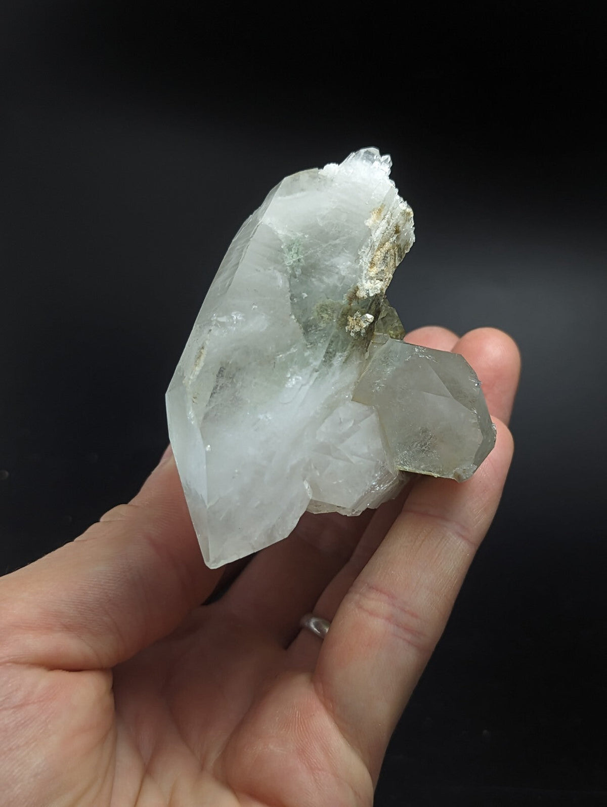 A translucent, pale quartz crystal cluster with a rough, earthy base and sharp, faceted points.