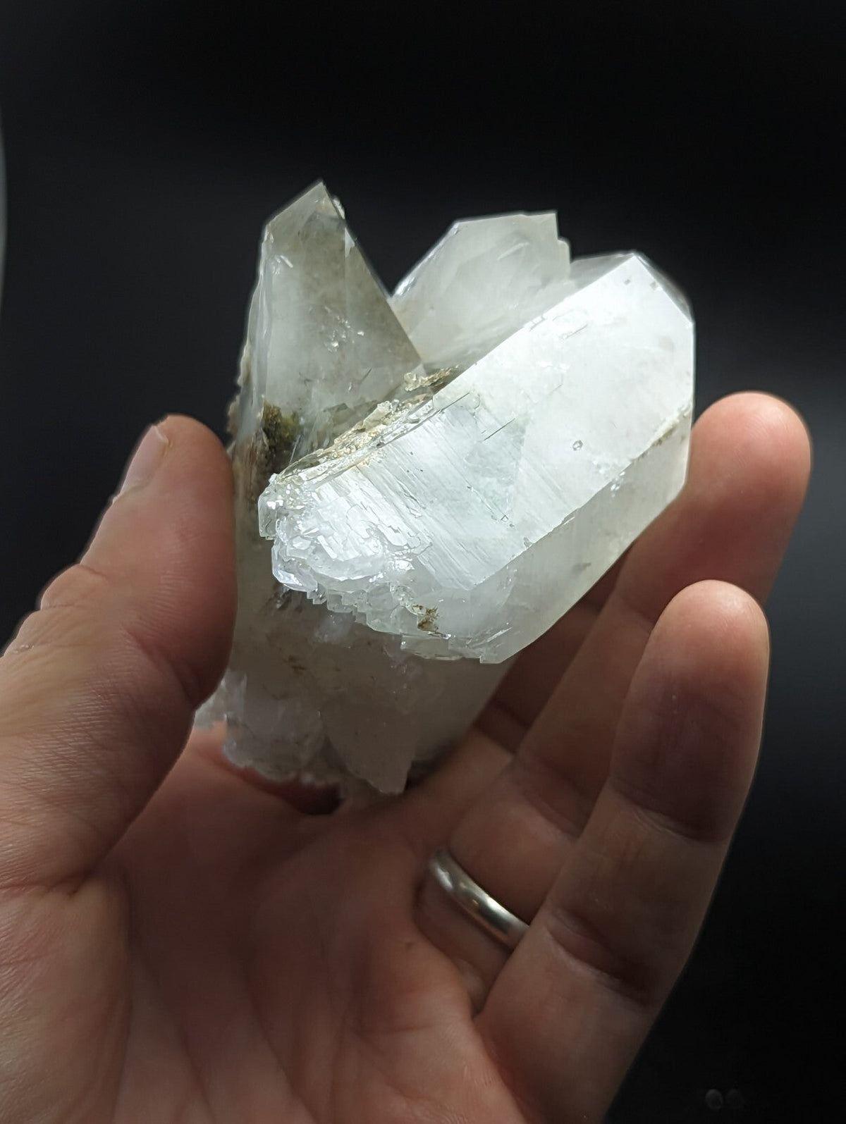 A translucent white quartz crystal cluster with sharp, faceted edges and a few greenish mineral inclusions.