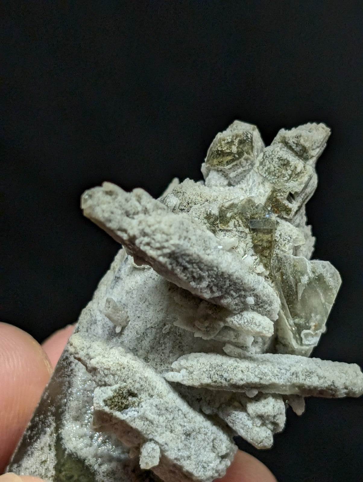 A cluster of pale green and white mineral crystals with a rough, jagged texture.