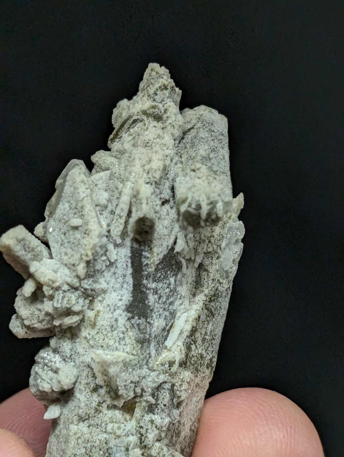 A grayish-white mineral specimen with jagged, crystalline formations and a rough, textured surface.