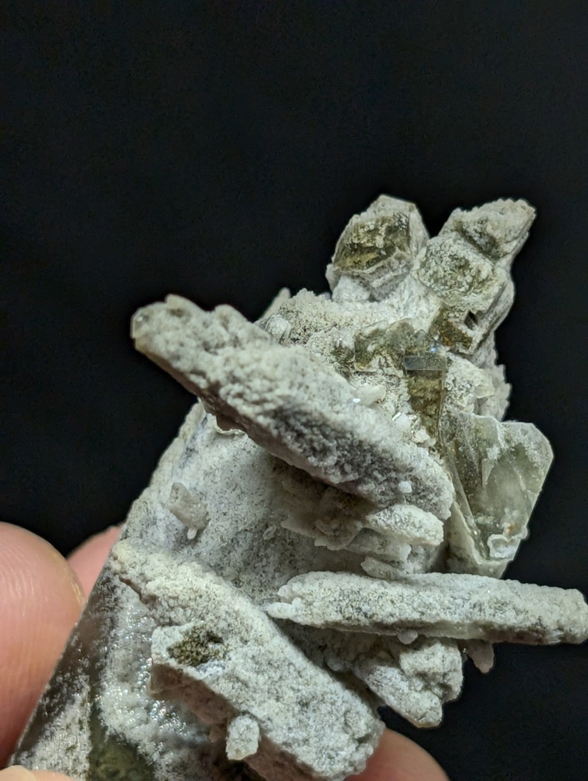 A cluster of pale green and white mineral crystals with a rough, jagged texture.