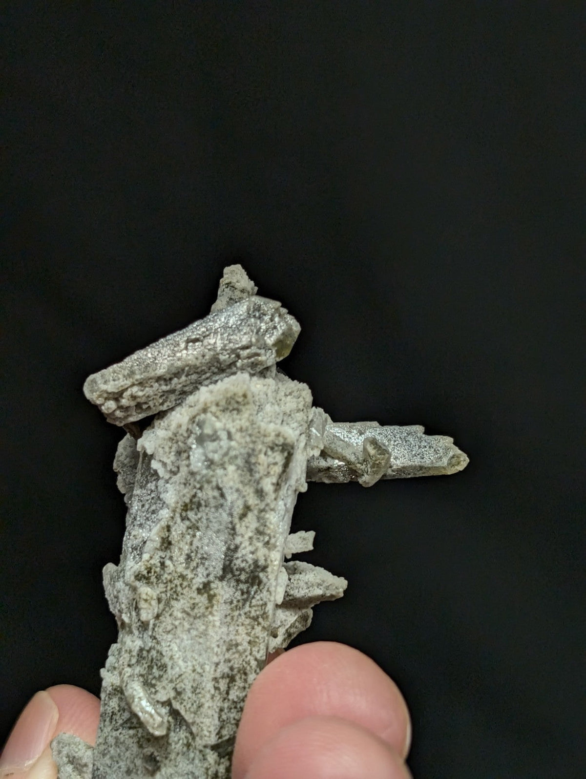 A gray, textured mineral specimen with crystalline formations and rough surfaces.