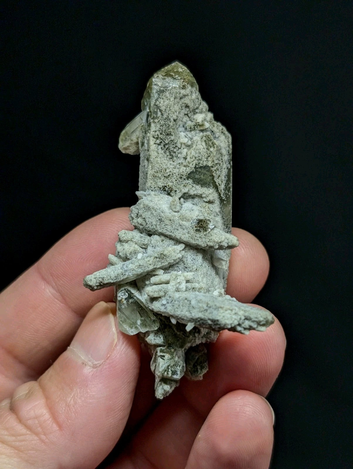 A textured, pale green mineral specimen with crystalline formations and a rough, natural surface.