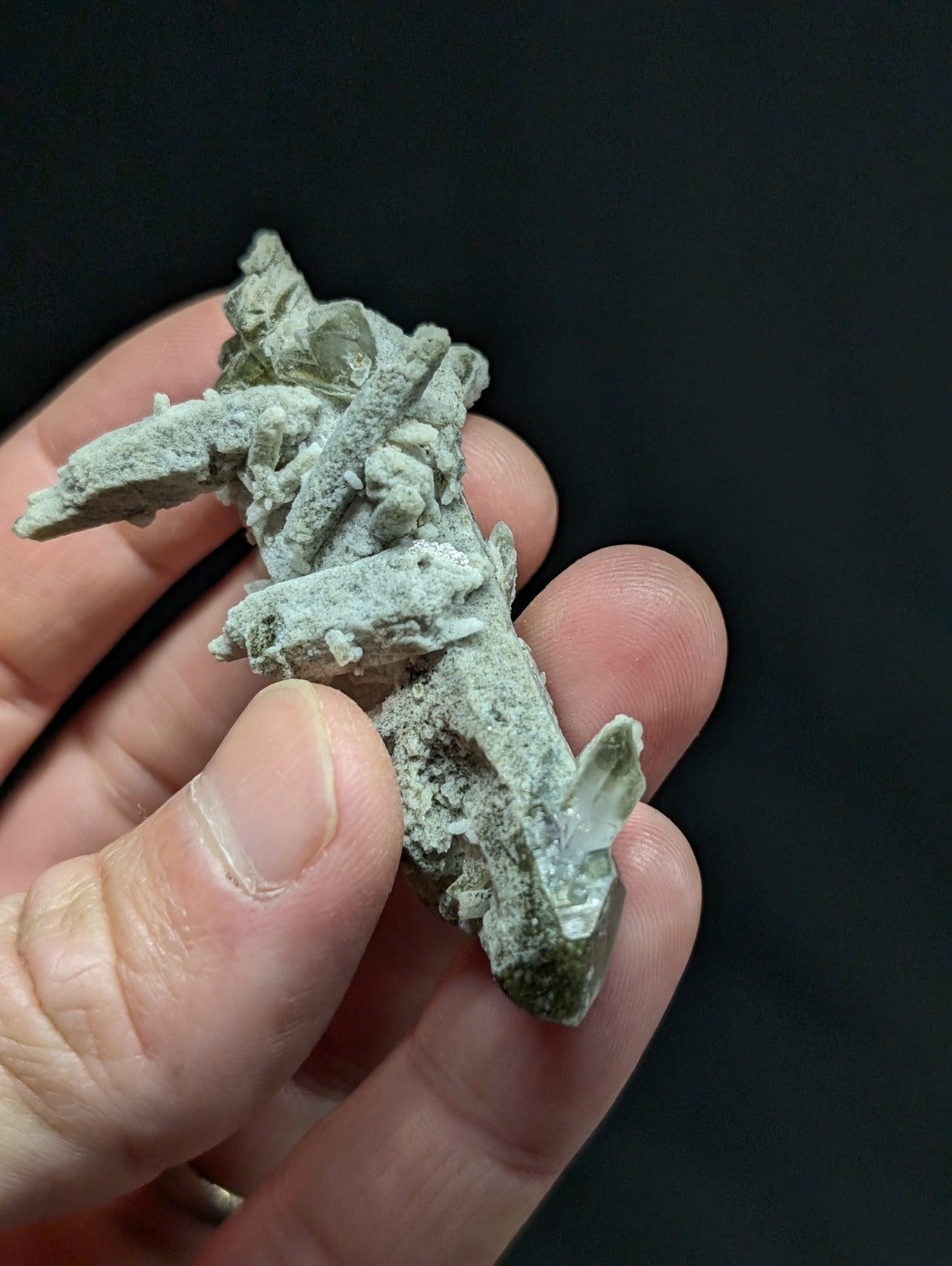 A pale green, crystalline mineral specimen with jagged edges and a rough, earthy texture.