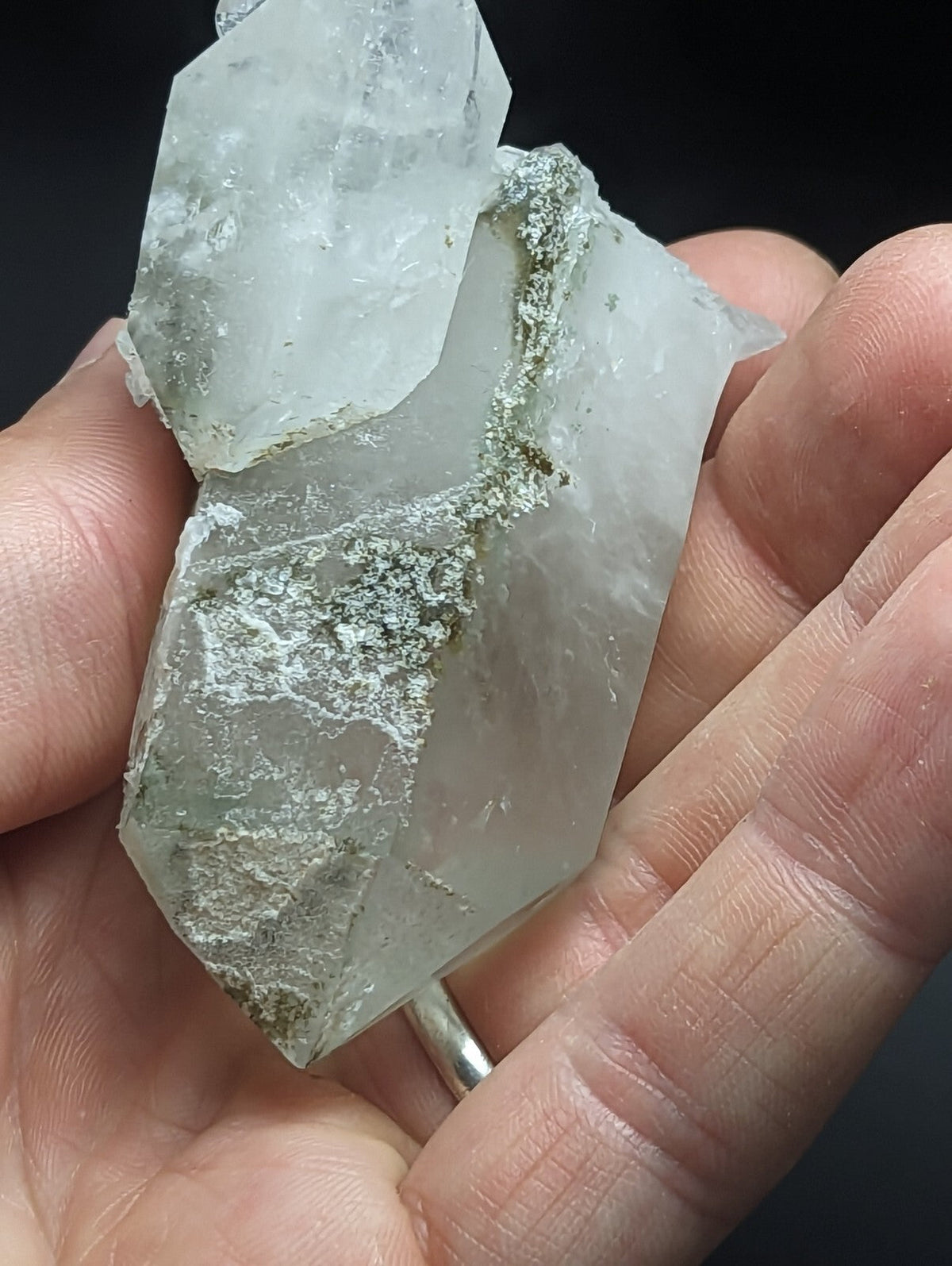 A translucent, pale green quartz crystal cluster with natural mineral inclusions and a silver-toned metal band at its base.