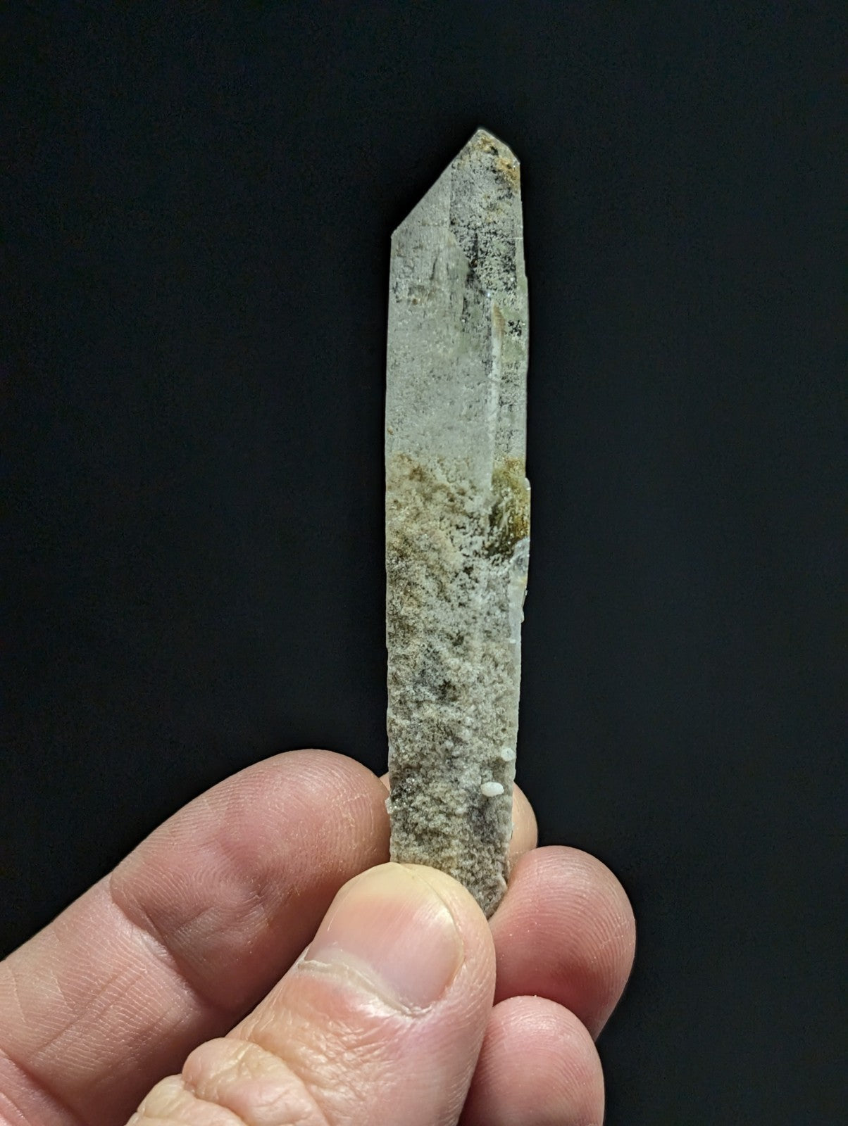 A translucent, pale green quartz crystal with natural mineral inclusions and a pointed tip.